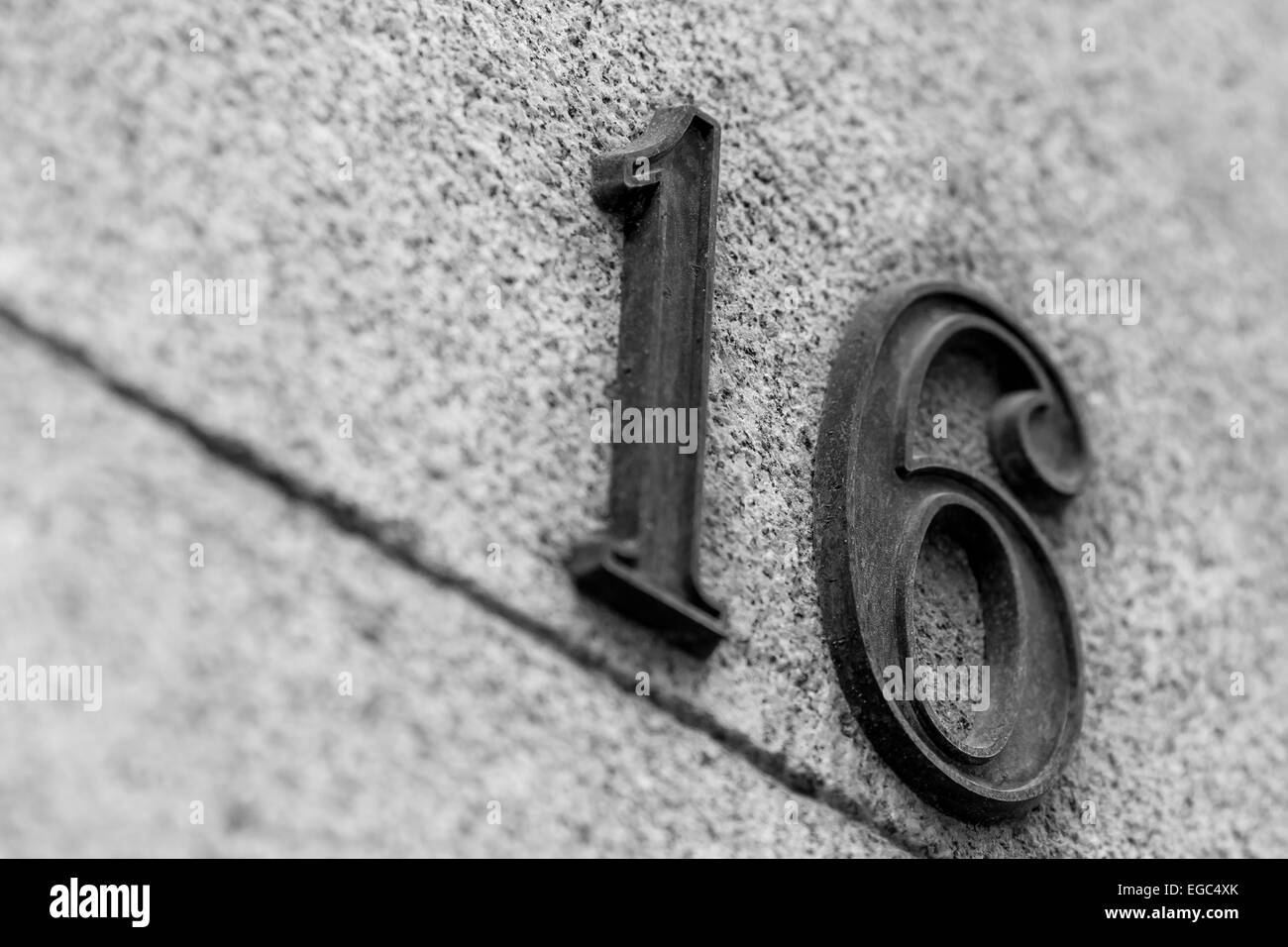 Numero metallico 16 su una parete di granito Foto Stock Numero metallico 16 su una parete di granito Foto Stock