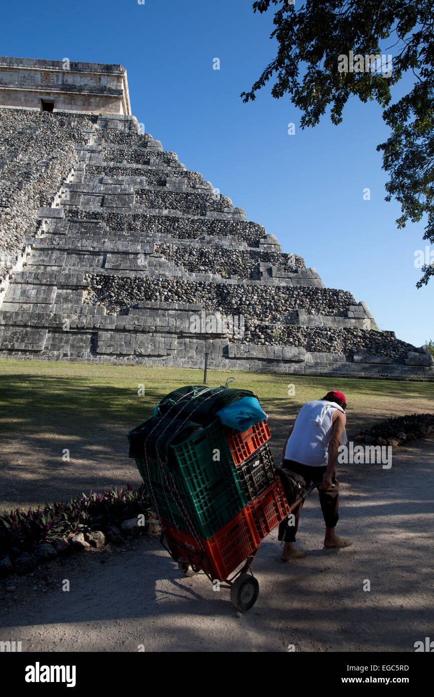 Un turista venditore souvenir cale la sua merce passato El Castillo, Chichen Itza, Yucatan, Messico Foto Stock