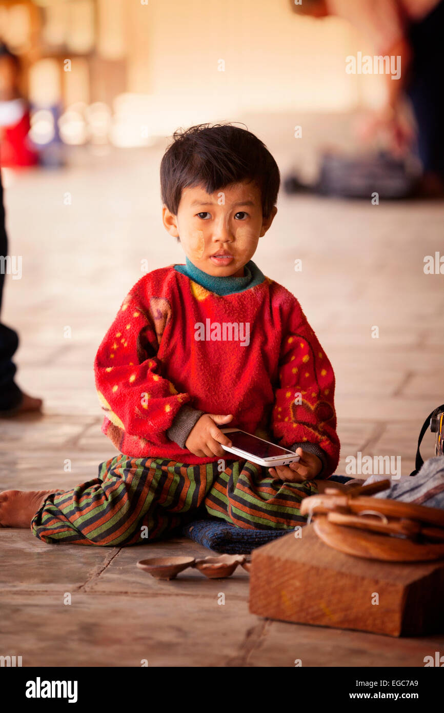 Un giovane ragazzo asiatico giocando con un telefono cellulare, Bagan, Myanmar ( Birmania ), Asia Foto Stock