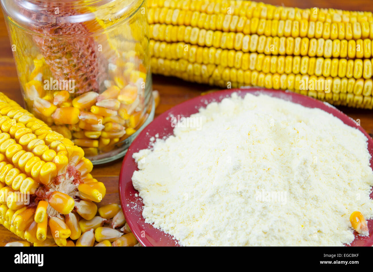 Un vaso con il mais, la farina di mais e orecchio su una tavola di legno Foto Stock