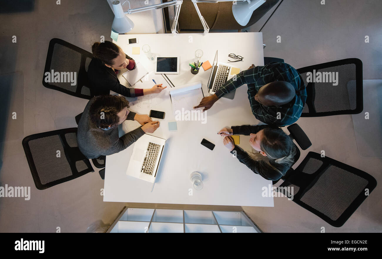 Vista aerea del team diversificato analizzando i dati mentre è seduto in ufficio. Multirazziale la gente di affari in occasione di un incontro di lavoro. Foto Stock