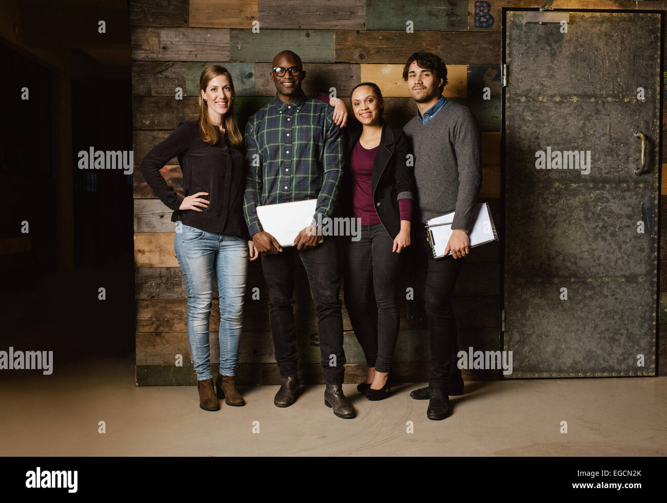 Ritratto di business di successo di squadra in piedi insieme contro la parete in legno. Lunghezza completa immagine di un gruppo di diversi colleghi Foto Stock