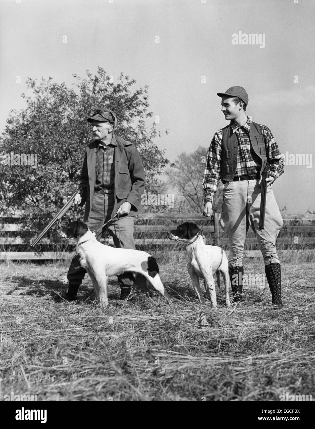 Trenta anni quaranta due uomini giovani e SENIOR ciascuno con un cane da caccia e tiro la pistola IN PIEDI IN UN CAMPO Foto Stock