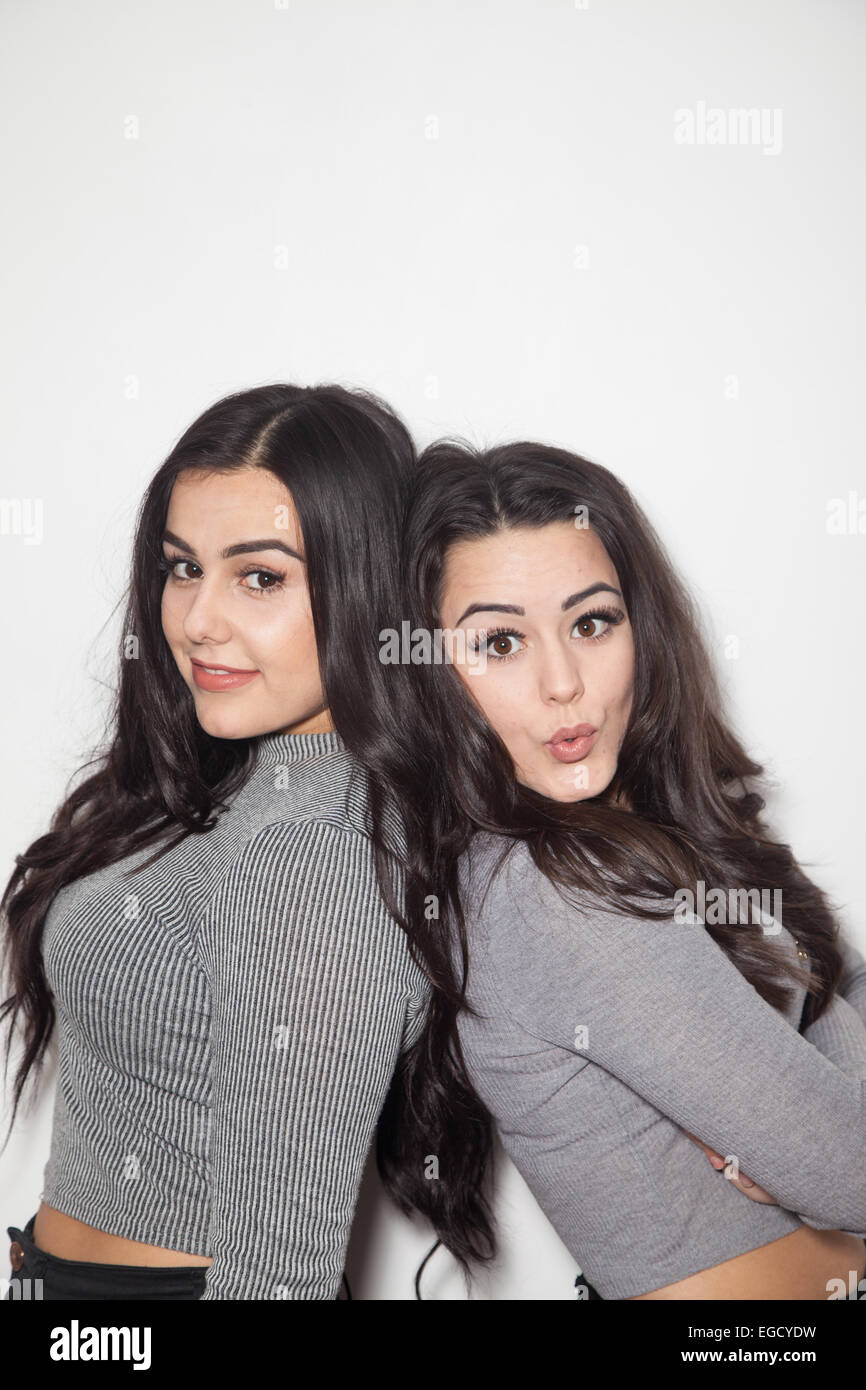 Due dai capelli scuri sorelle appoggiata di schiena. Foto Stock