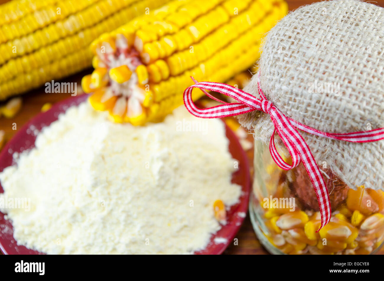 Un vaso con il mais, la farina di mais e orecchio su una tavola di legno Foto Stock