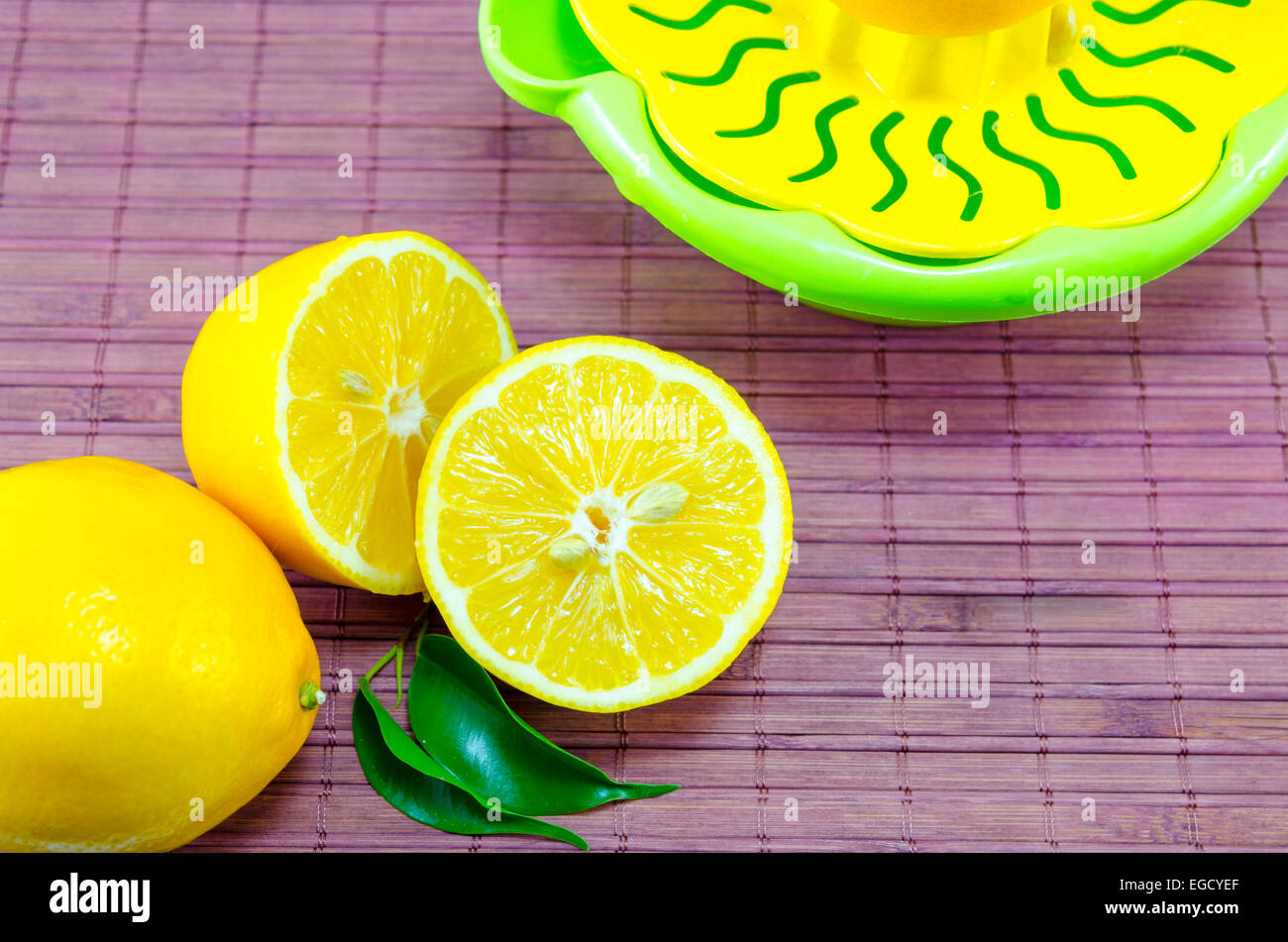 Dimezzato i limoni e uno scolapasta su un viola superficie di bambù Foto Stock