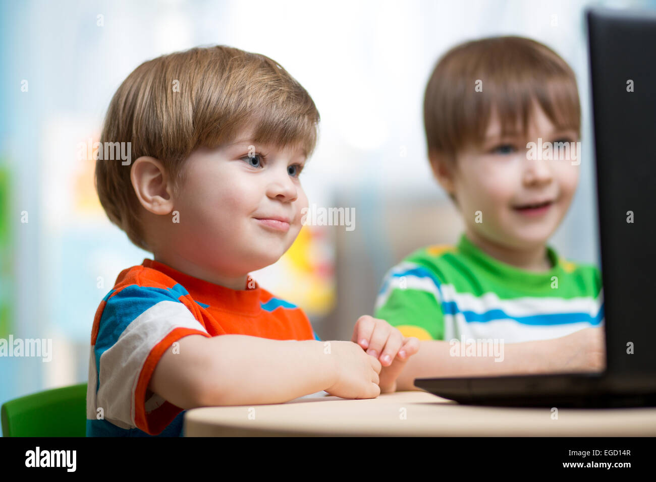 Dei bambini felici giocando al laptop Foto Stock