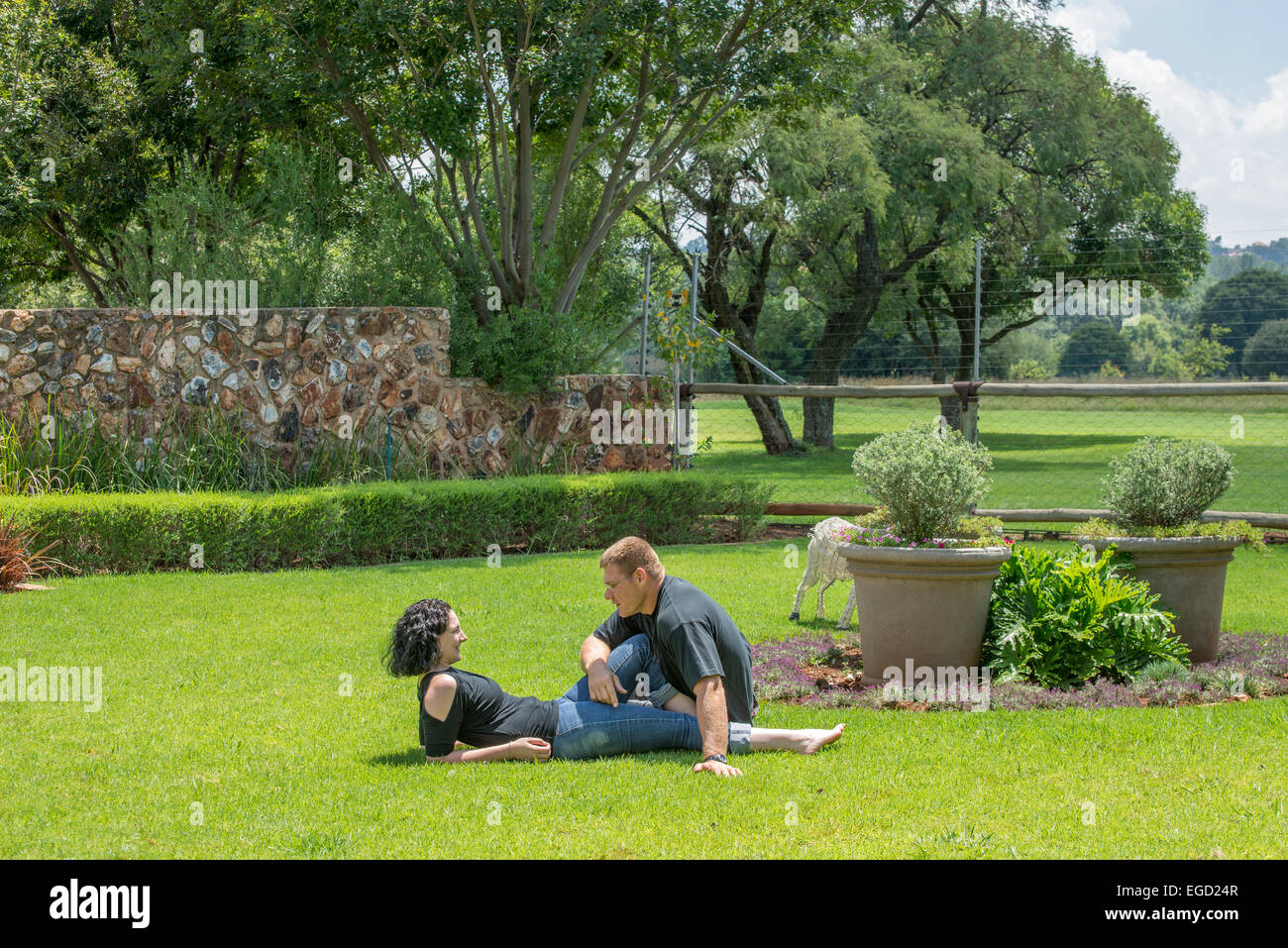 Un paio di sedersi sul prato nel loro giardino godendo il bel tempo estivo, chiacchierando con ogni altro. Foto Stock