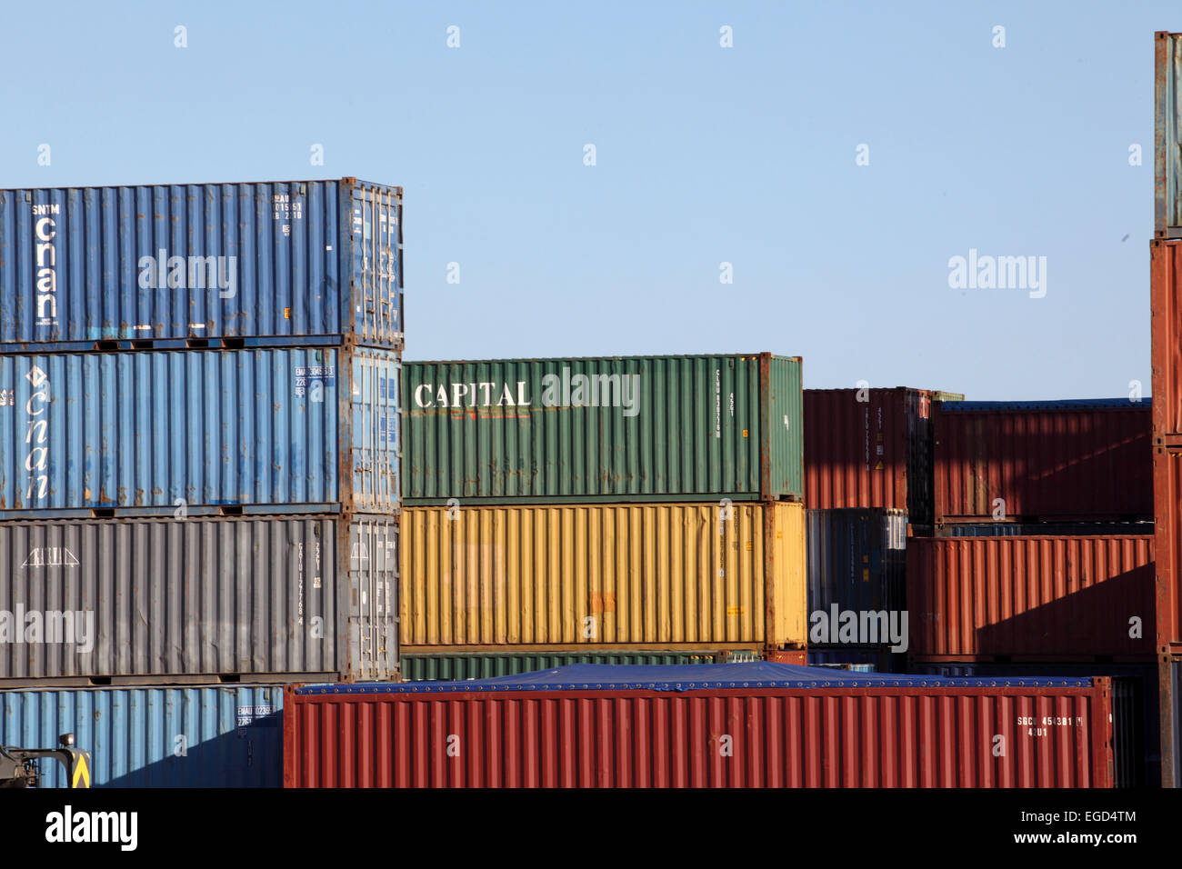 Contrastanti e colorato di pile di contenitori di spedizione ammucchiati uno a Barcellona docks. Foto Stock