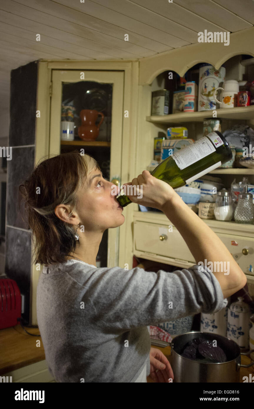 Una donna matura di bere alcol direttamente dalla bottiglia Foto Stock