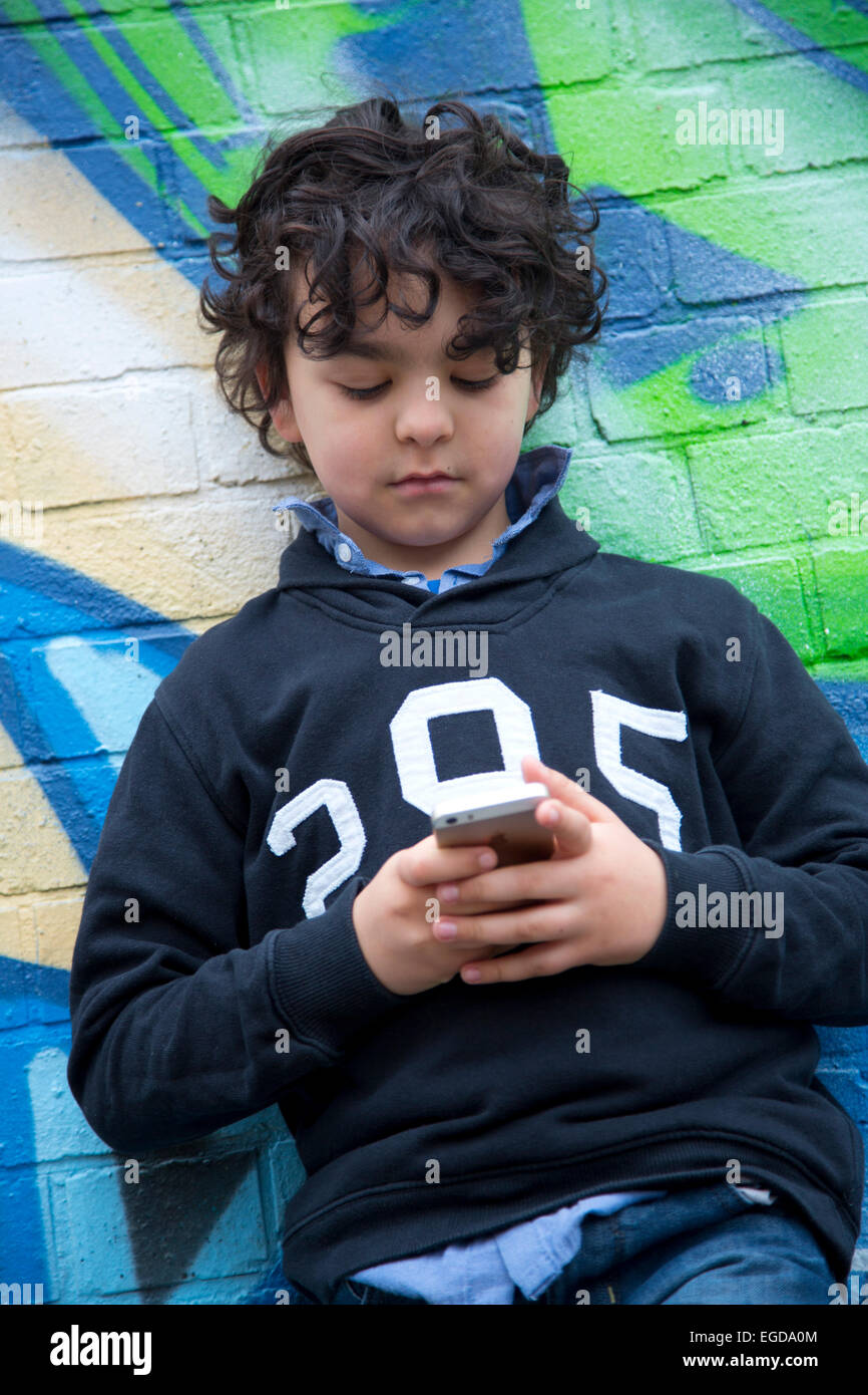 8 anno vecchio ragazzo tramite telefono cellulare Foto Stock
