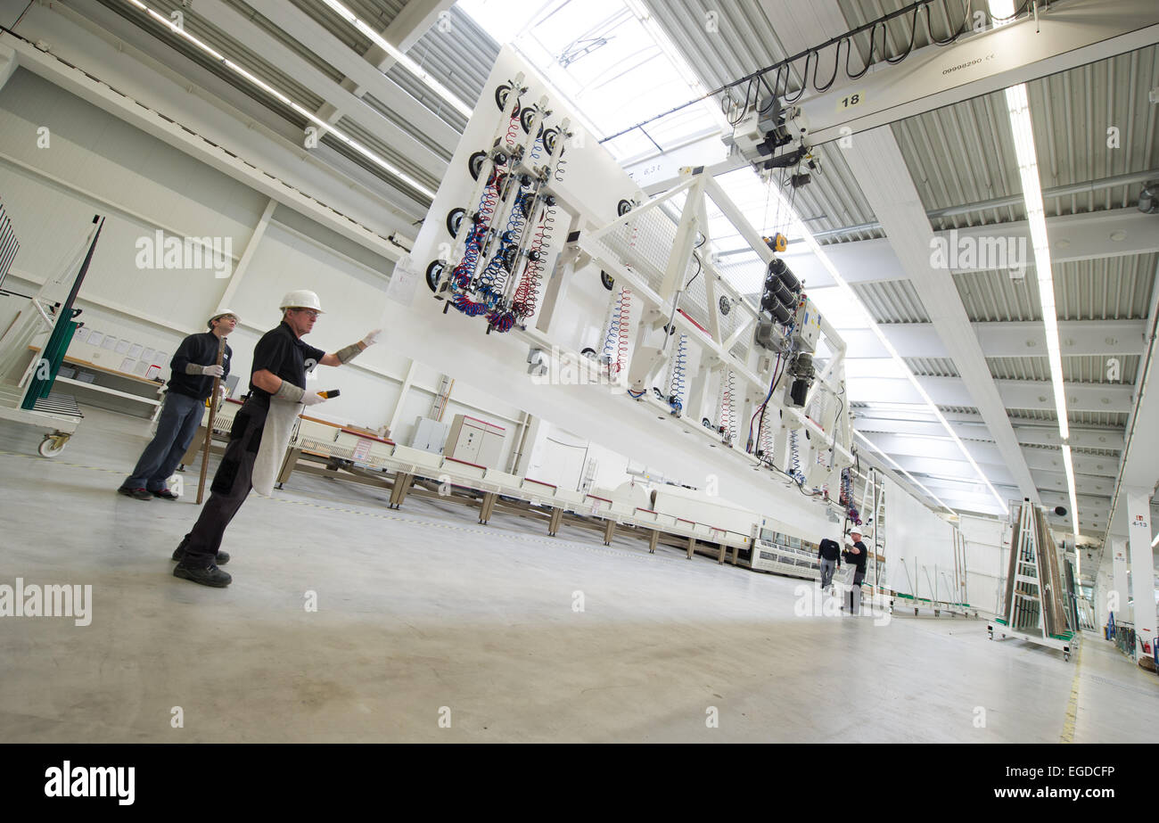 Gersthofen, Germania. Il 23 febbraio, 2015. Lavoratori in fabbrica trasportare una lastra di vetro con una gru a Seele i fabbricanti di vetro Gersthofen, Germania, 23 febbraio 2015. Seele rende il vetro delle scale per tutti i negozi Apple Store di tutto il mondo e produce anche le lastre di vetro per le facciate del nuovo Apple Campus 2. Foto: Tobias Hase/dpa/Alamy Live News Foto Stock