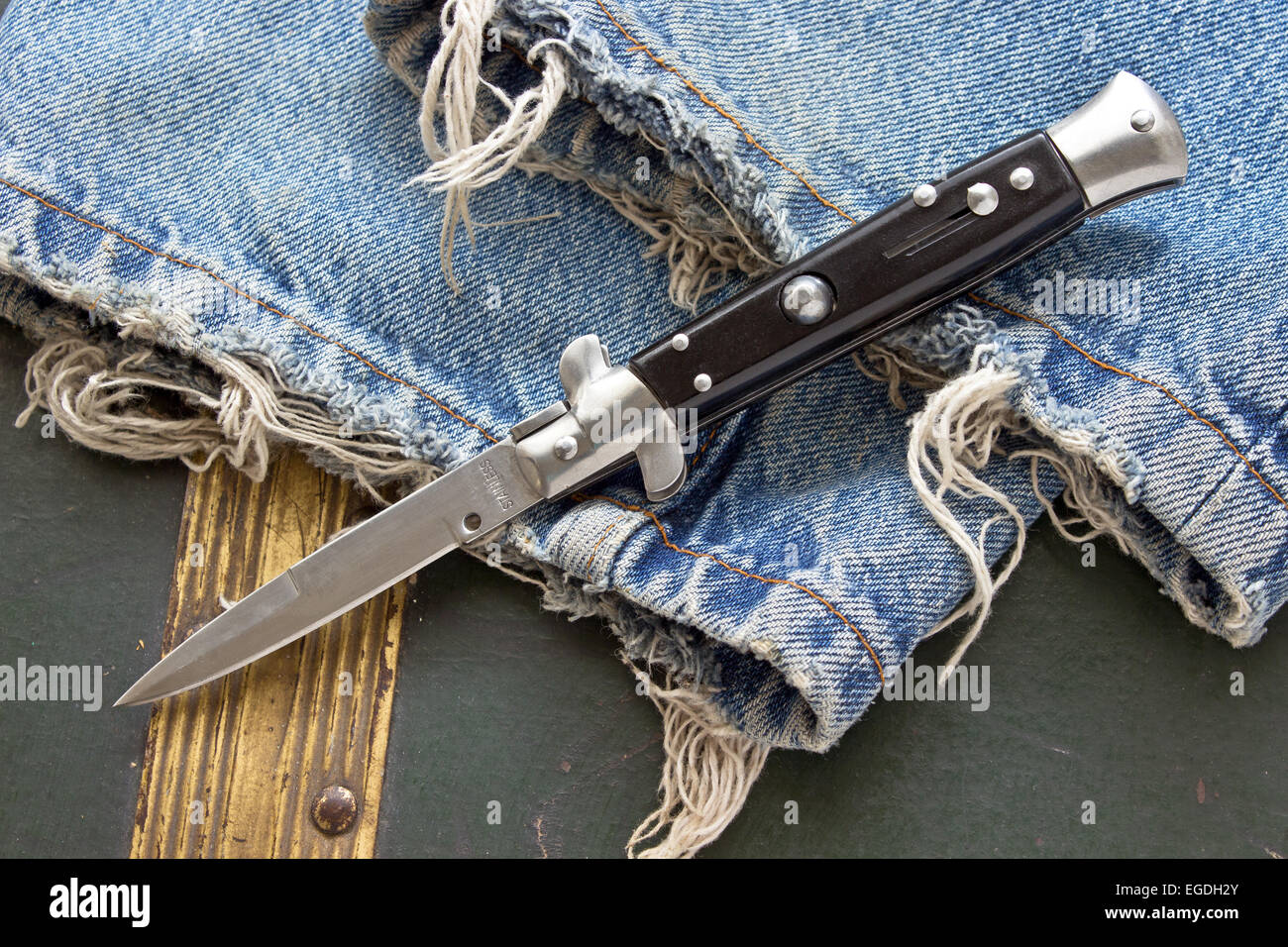 Switchblade coltello su vecchi jeans blu Foto Stock