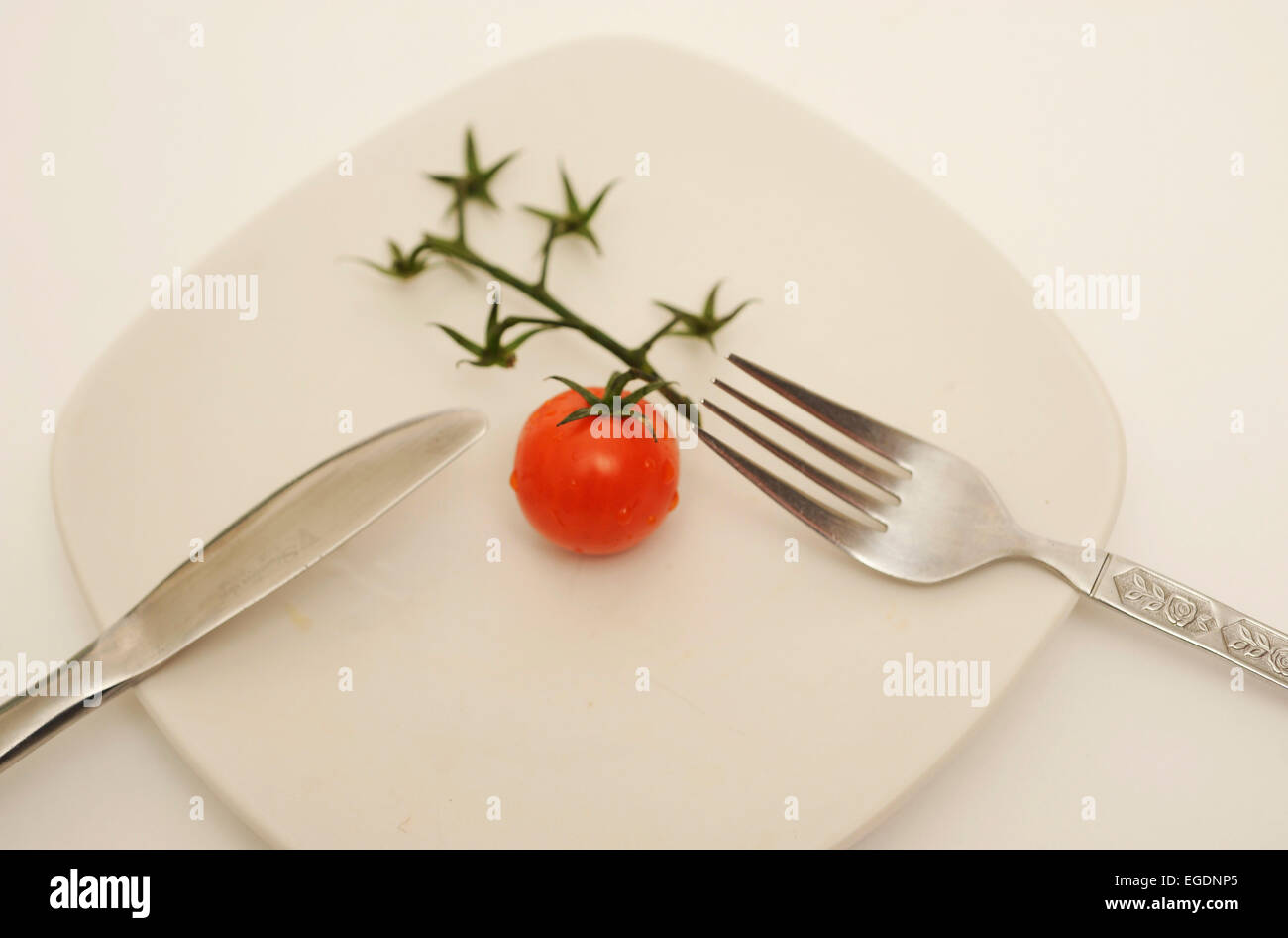 Pomodoro su piastra con posate Foto Stock