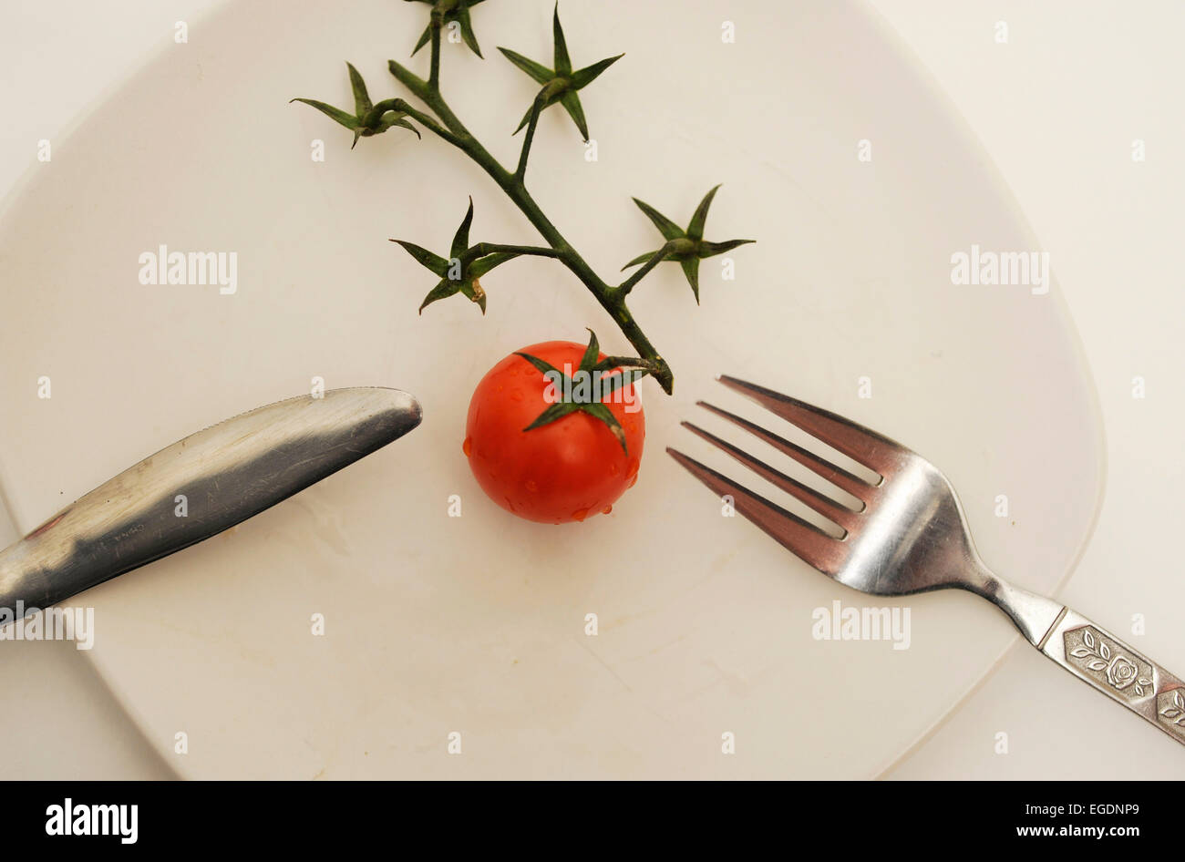 Pomodoro su piastra con posate Foto Stock