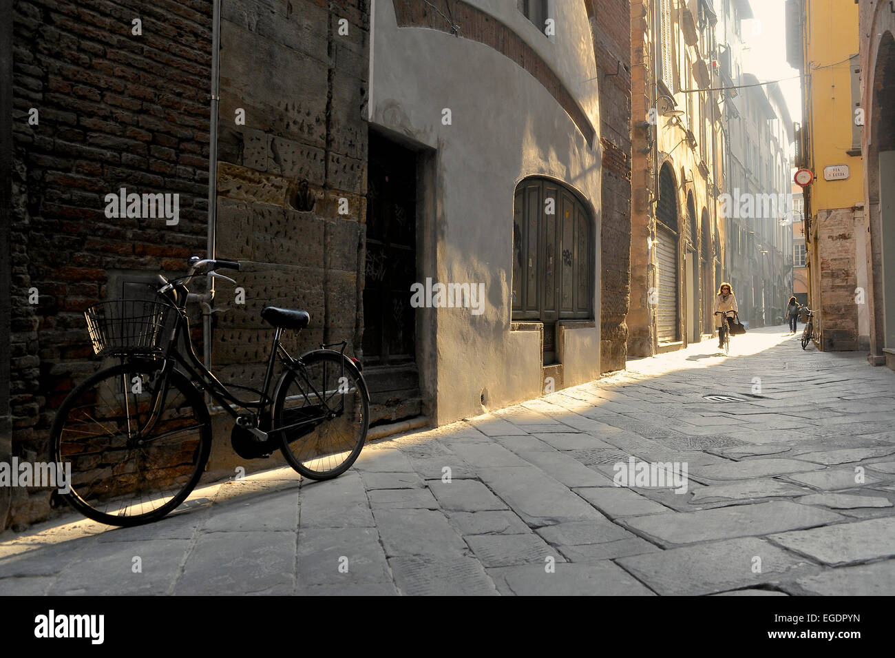 In bicicletta in un vicolo stretto nella luce del mattino a Lucca, Toscana, Italia Foto Stock