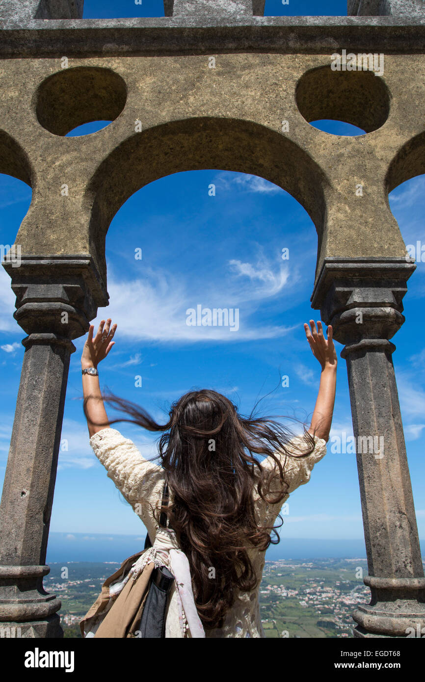 Donna con le braccia sollevate, guardando attraverso una apertura in corrispondenza del Palacio Nacional da Pena (Pena Palazzo Nazionale), Sintra, Estremadura, Portogallo Foto Stock