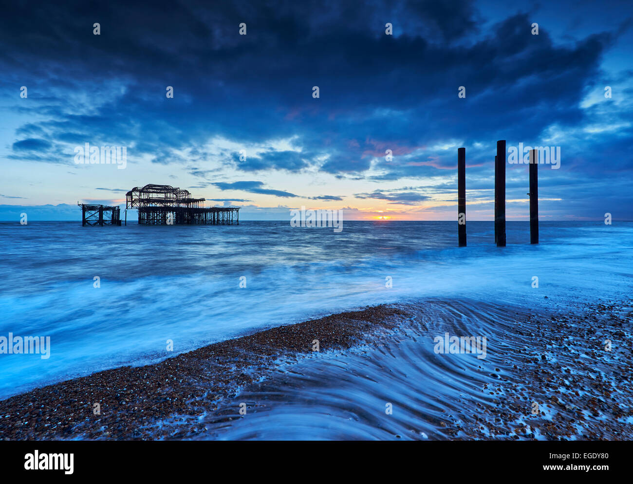 Decadimento rimane di Brighton il Molo Ovest al tramonto con la marea. Foto Stock