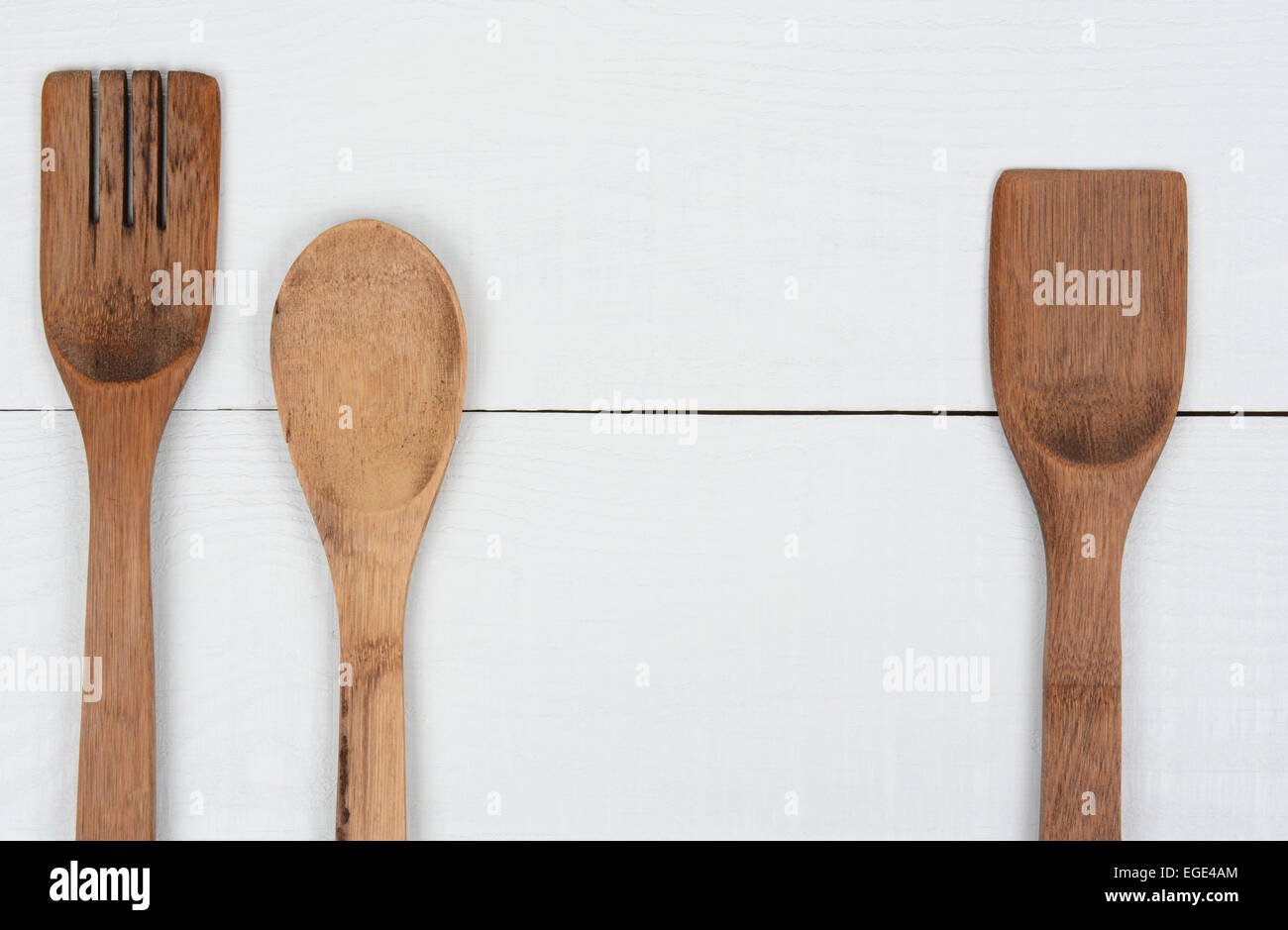 Angolo alto ingrandimento di un cucchiaio di legno, forcella e la spatola, su di un legno bianco tavolo da cucina. Formato orizzontale con spazio copia in Foto Stock