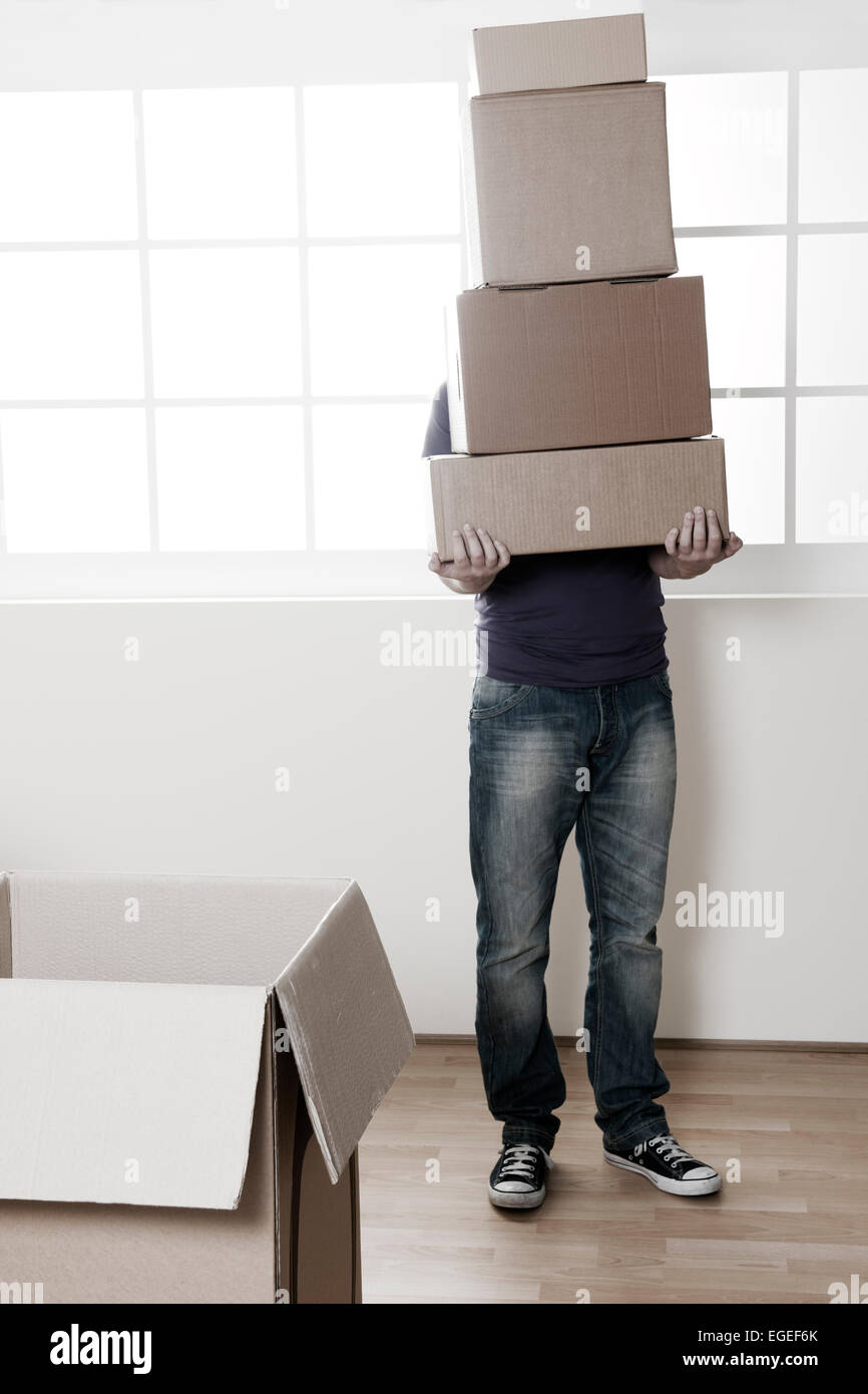 Uomo che trasportava scatole impilate sul giorno del trasloco, dissaturato immagine Foto Stock