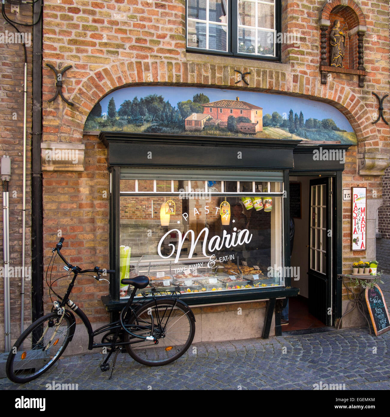 BRUGES, BELGIO, Regno Unito - 13 APRILE 2014: Old Bike al di fuori dell'attraente ristorante Take-away Maria in Sint-Salvatorskerkhof Street Bruges Foto Stock