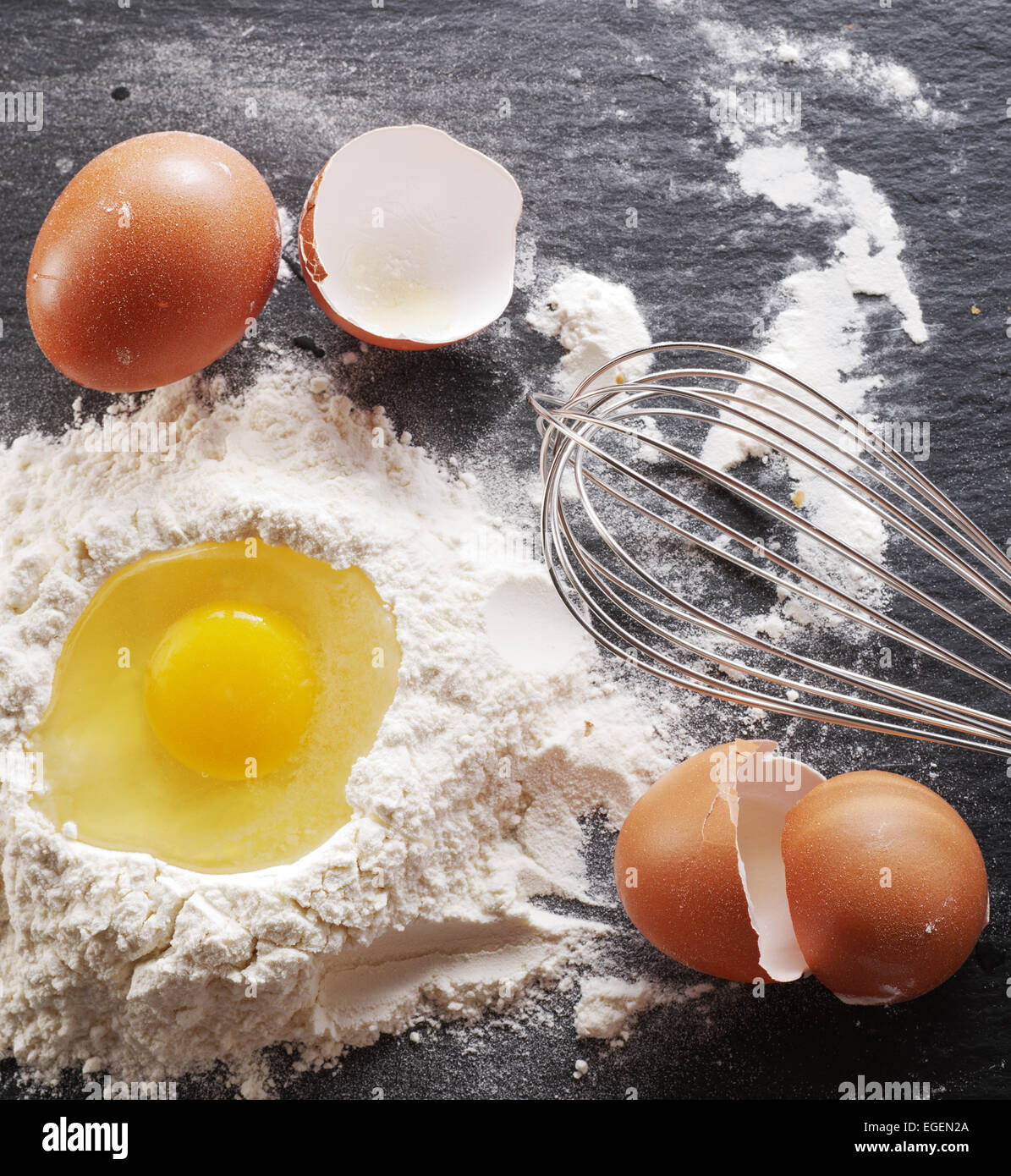 Preparazione di pasta. La cottura Ingredienti: uova e farina sul bordo nero. Foto Stock