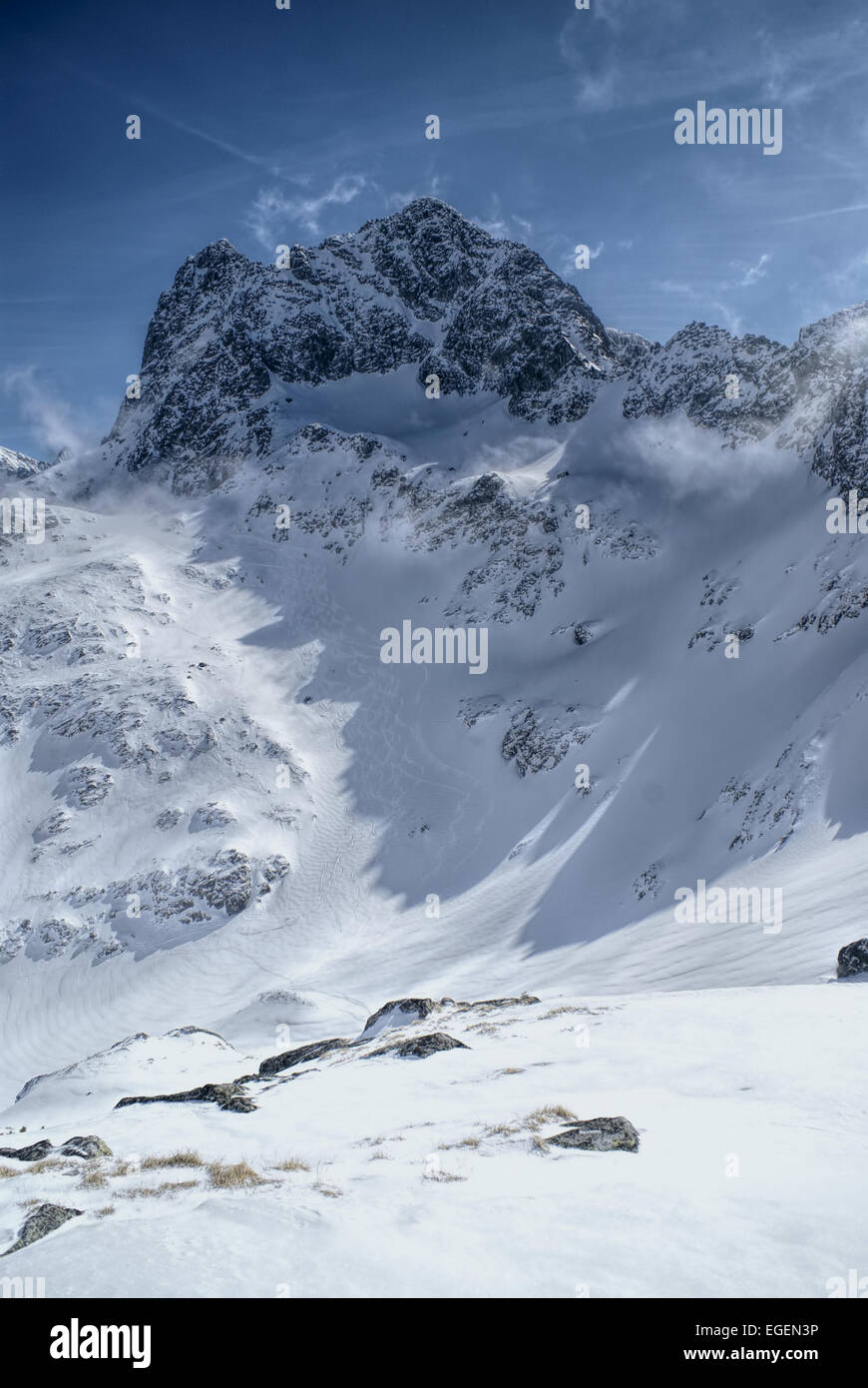 Più mozzafiato di picchi rocciosi nascosta nell'ombra con il sole che splende su pendii innevati Foto Stock