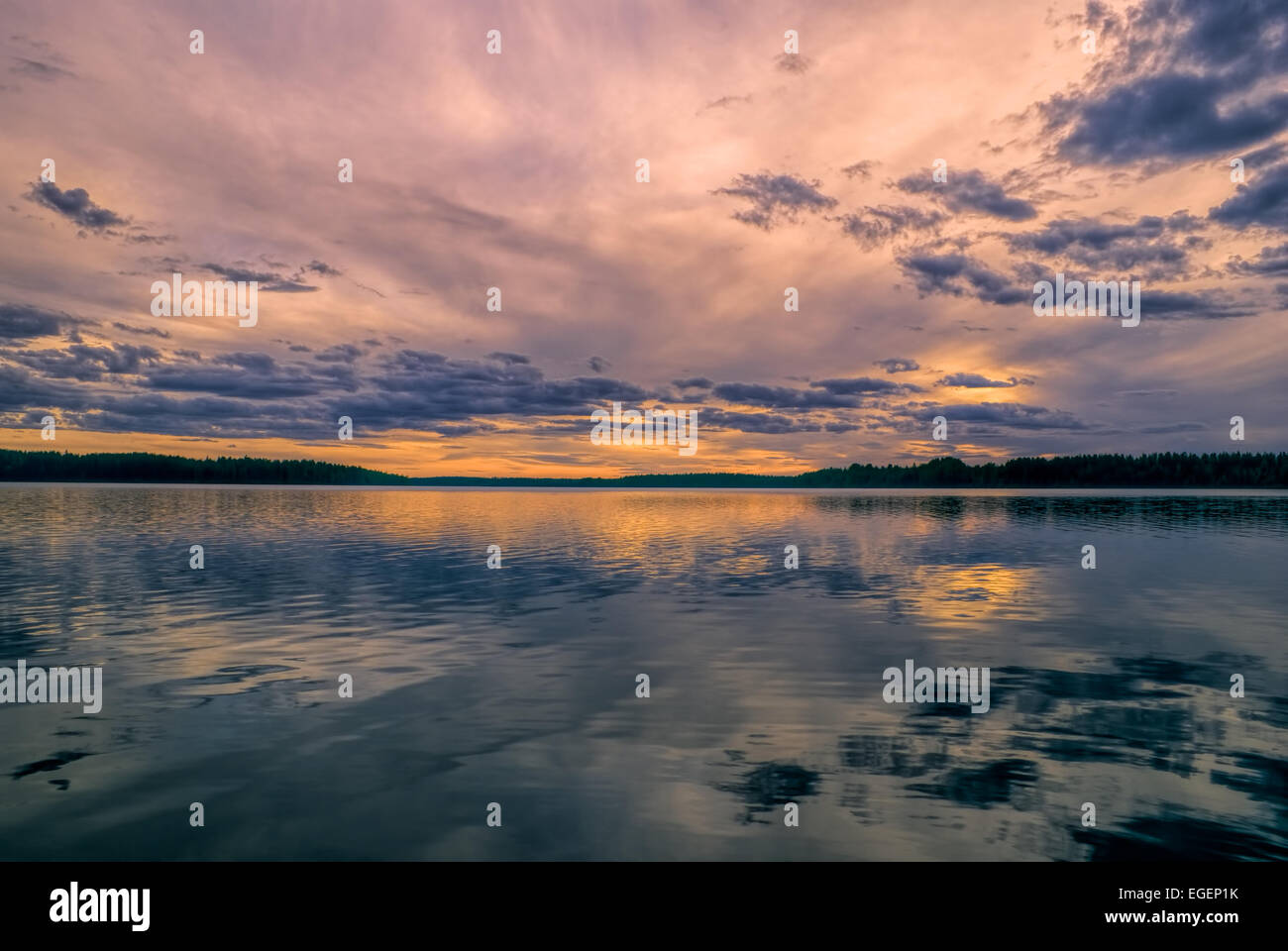 Vista mozzafiato del tramonto dietro il cielo ventoso riflessa in un lago Foto Stock