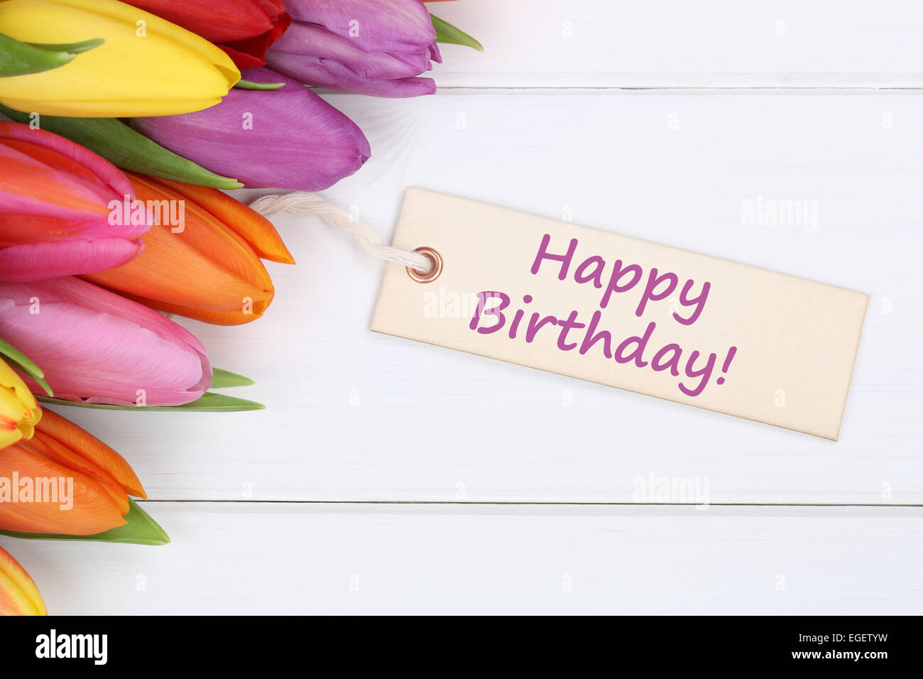 Buon compleanno con tulipani fiori su un bianco tavola di legno Foto Stock