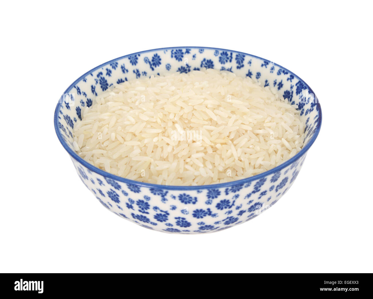Bianco di riso a grani lunghi in un blu e bianca porcellana ciotola con un design floreale, isolato su sfondo bianco Foto Stock