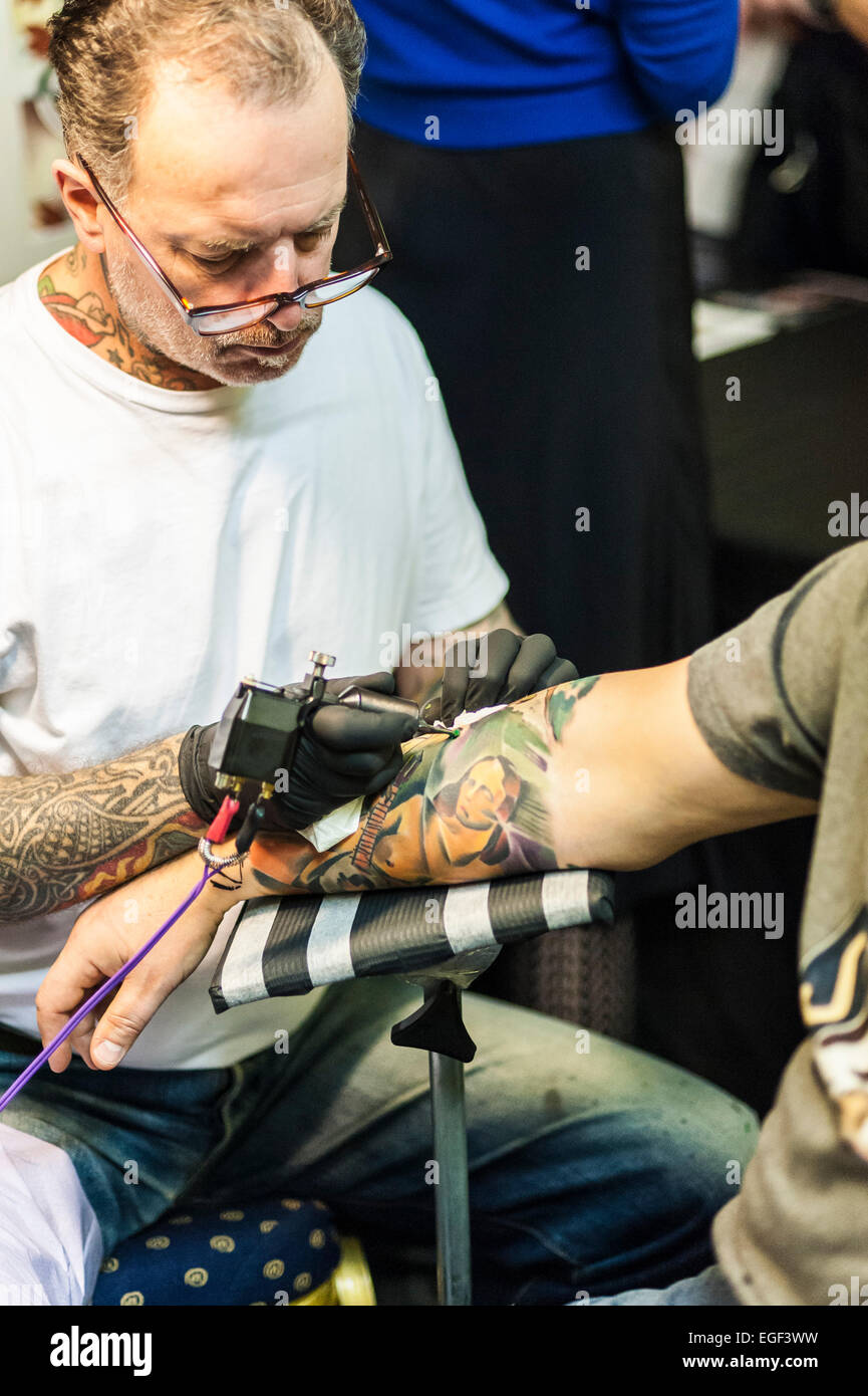 Un uomo tatuato sul suo braccio al Brighton Tattoo Convention. Foto Stock