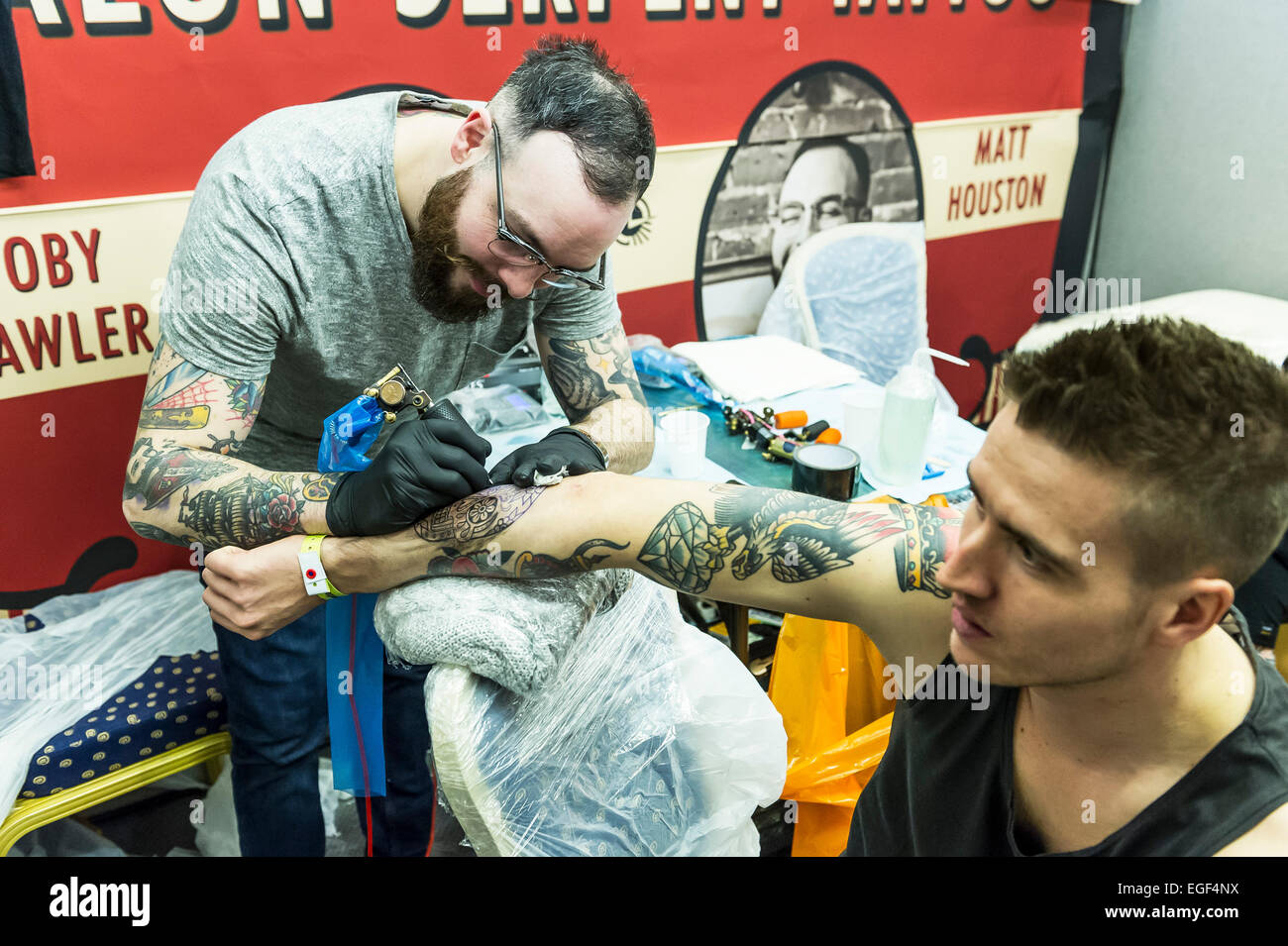 Un uomo tatuato sul suo braccio al Brighton Tattoo Convention. Foto Stock
