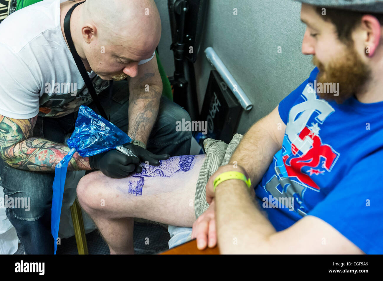 Un uomo tatuato sulla sua gamba al Brighton Tattoo Convention. Foto Stock