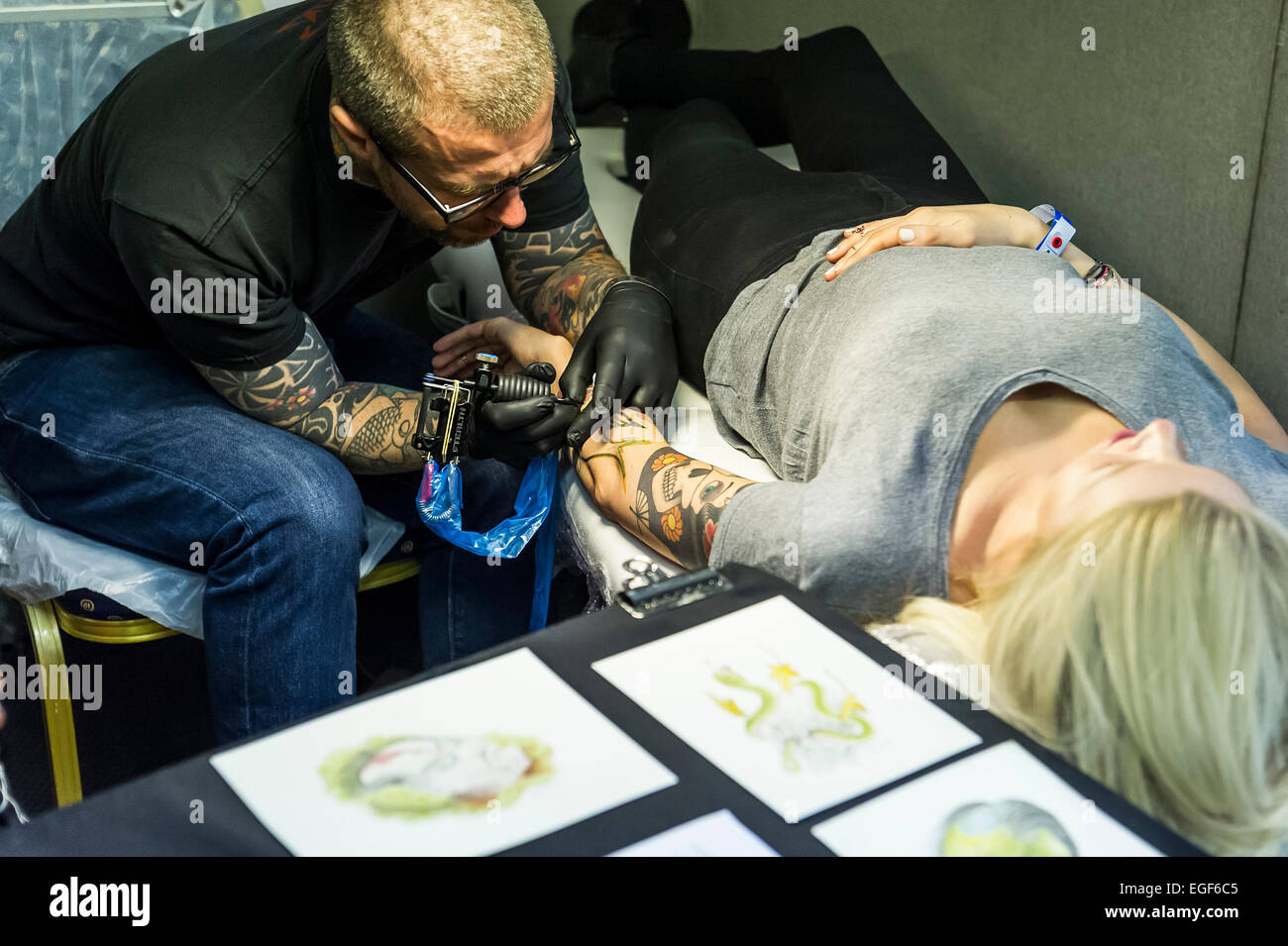 Una donna è tatuata sul suo braccio al Brighton Tattoo Convention. Foto Stock