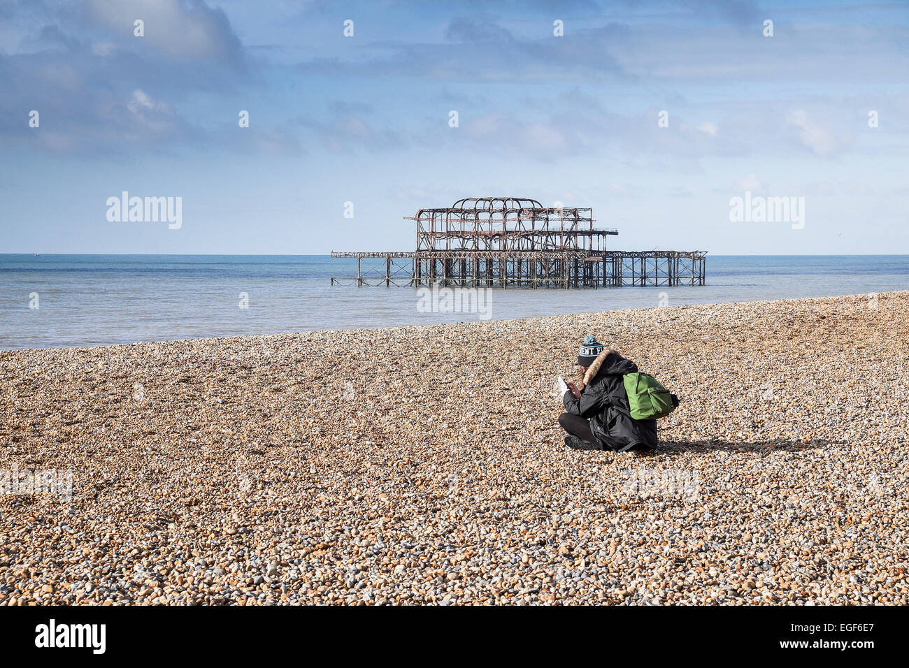 Una donna seduta sulla spiaggia di Brighton. Foto Stock