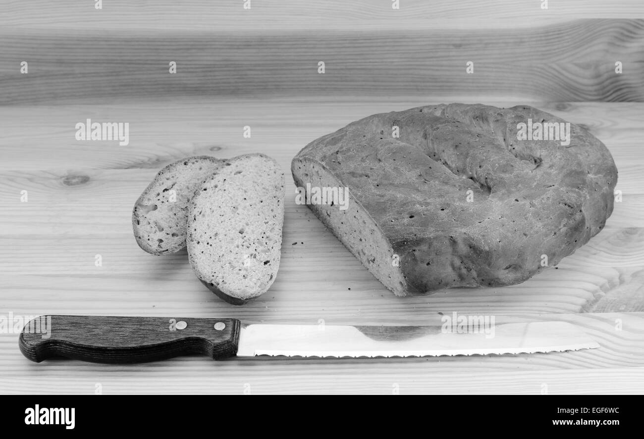 Coltello per pane con fette di pane tagliate da un seminato pagnotta di pane - elaborazione monocromatica Foto Stock