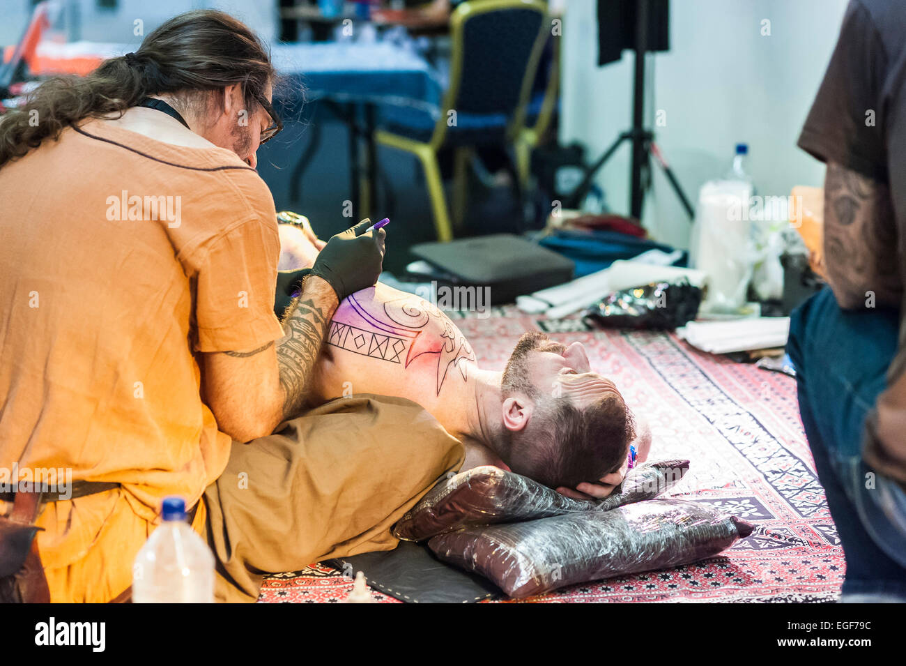 Una marcatura tattooist il corpo di un uomo con un disegno prima di tatuaggio al Brighton Tattoo Convention. Foto Stock