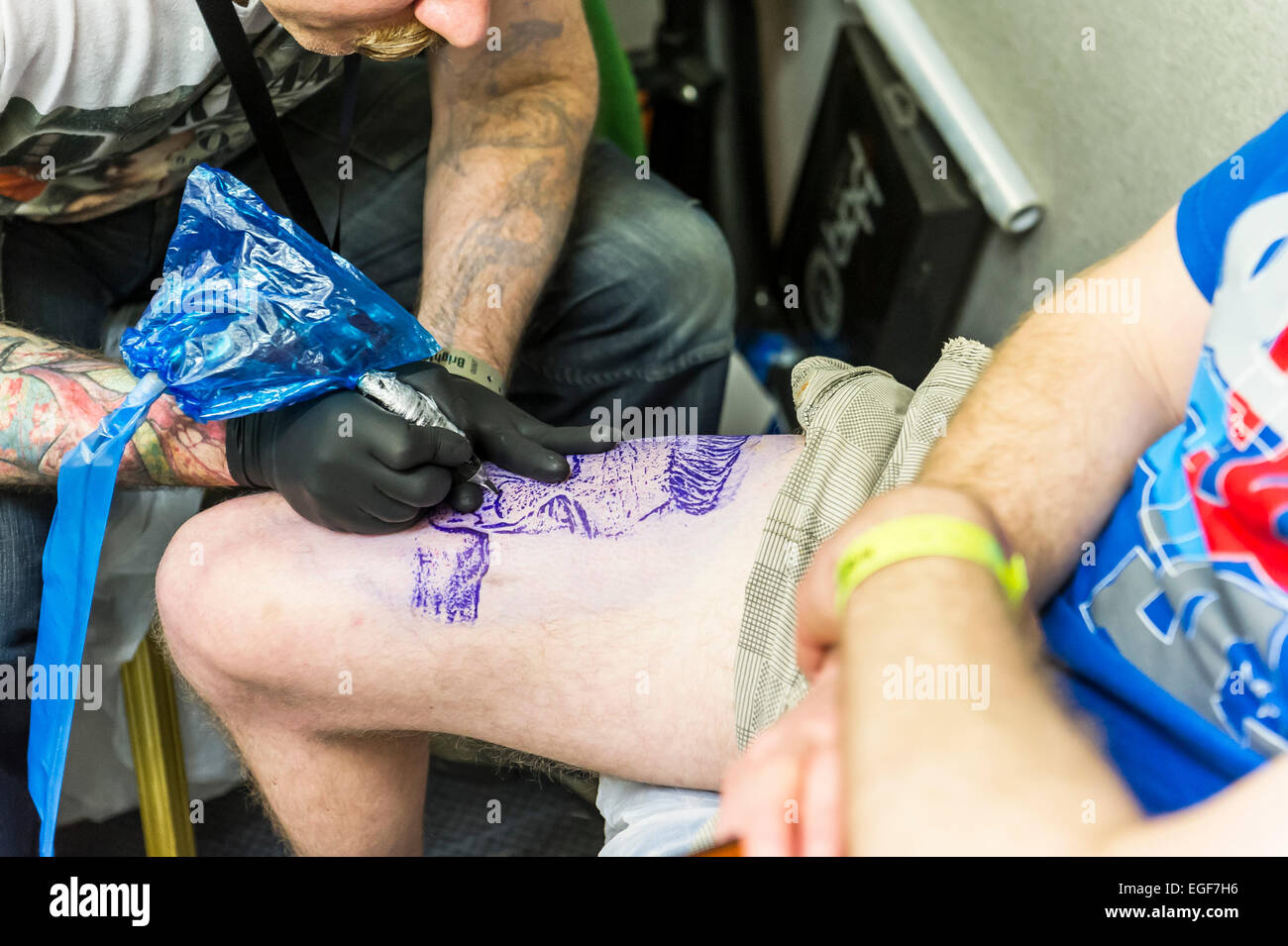 Un uomo tatuato sulla sua gamba al Brighton Tattoo Convention. Foto Stock