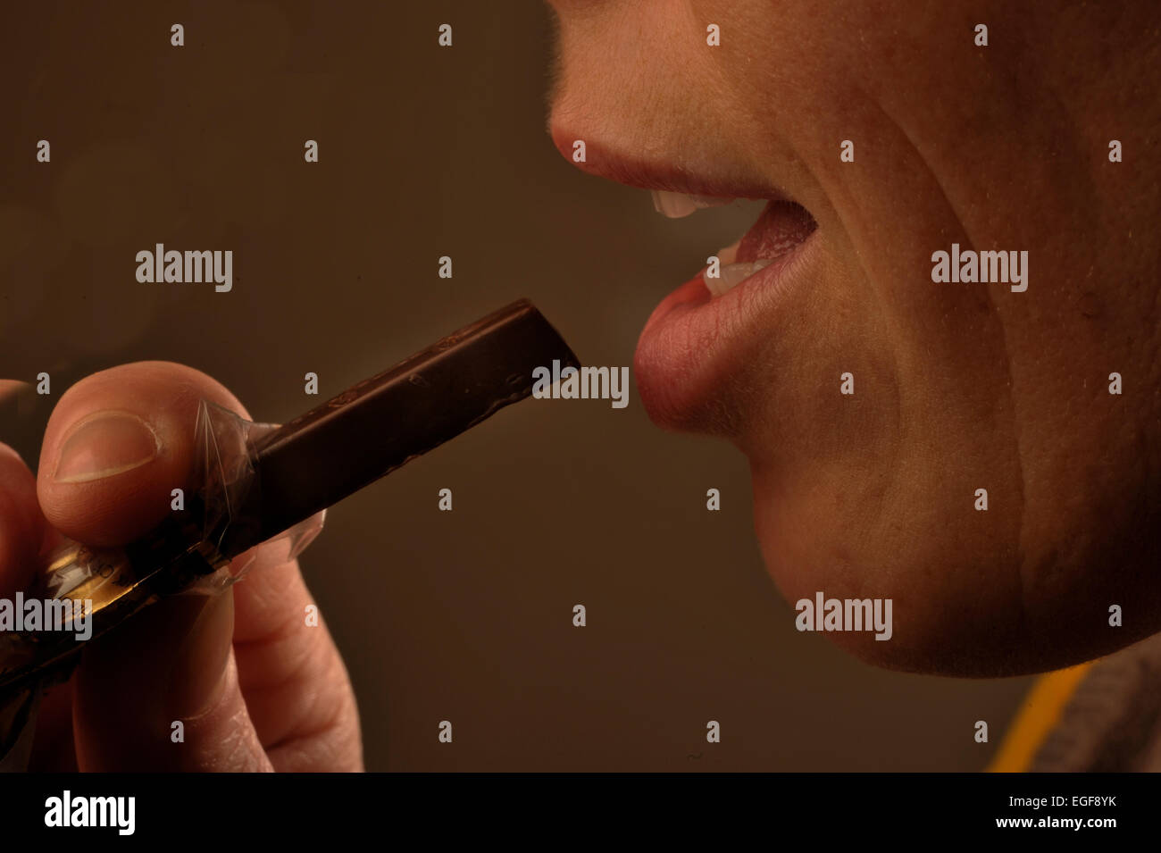 Immagine simbolica circa zucchero negli alimenti: Donna mangiare cioccolato. Foto Stock