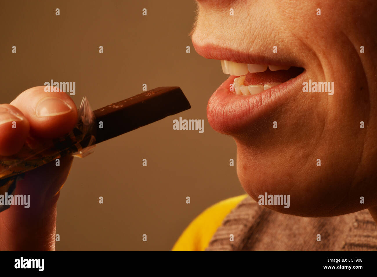 Immagine simbolica circa zucchero negli alimenti: Donna mangiare cioccolato. Foto Stock