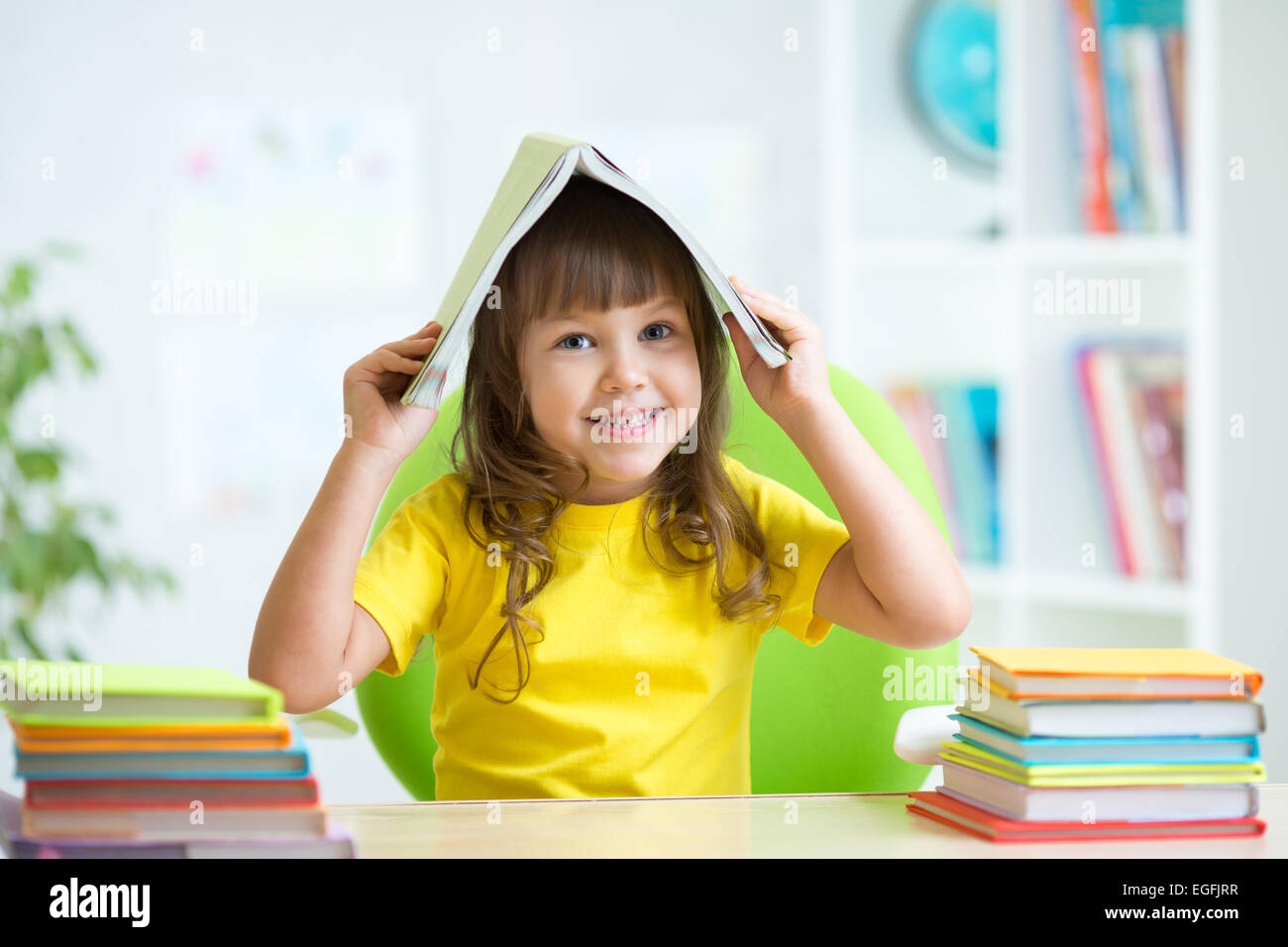 Bambino sorridente con un libro sulla sua testa Foto Stock
