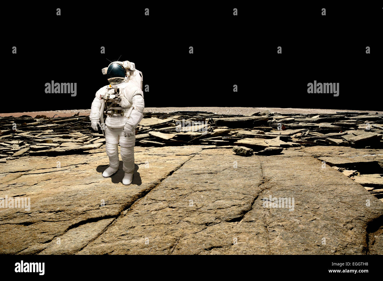 Un astronauta sondaggi la sua situazione dopo essere stata fregata su un pianeta sterile. La quantità di nero dello spazio profondo è lo sfondo. Foto Stock