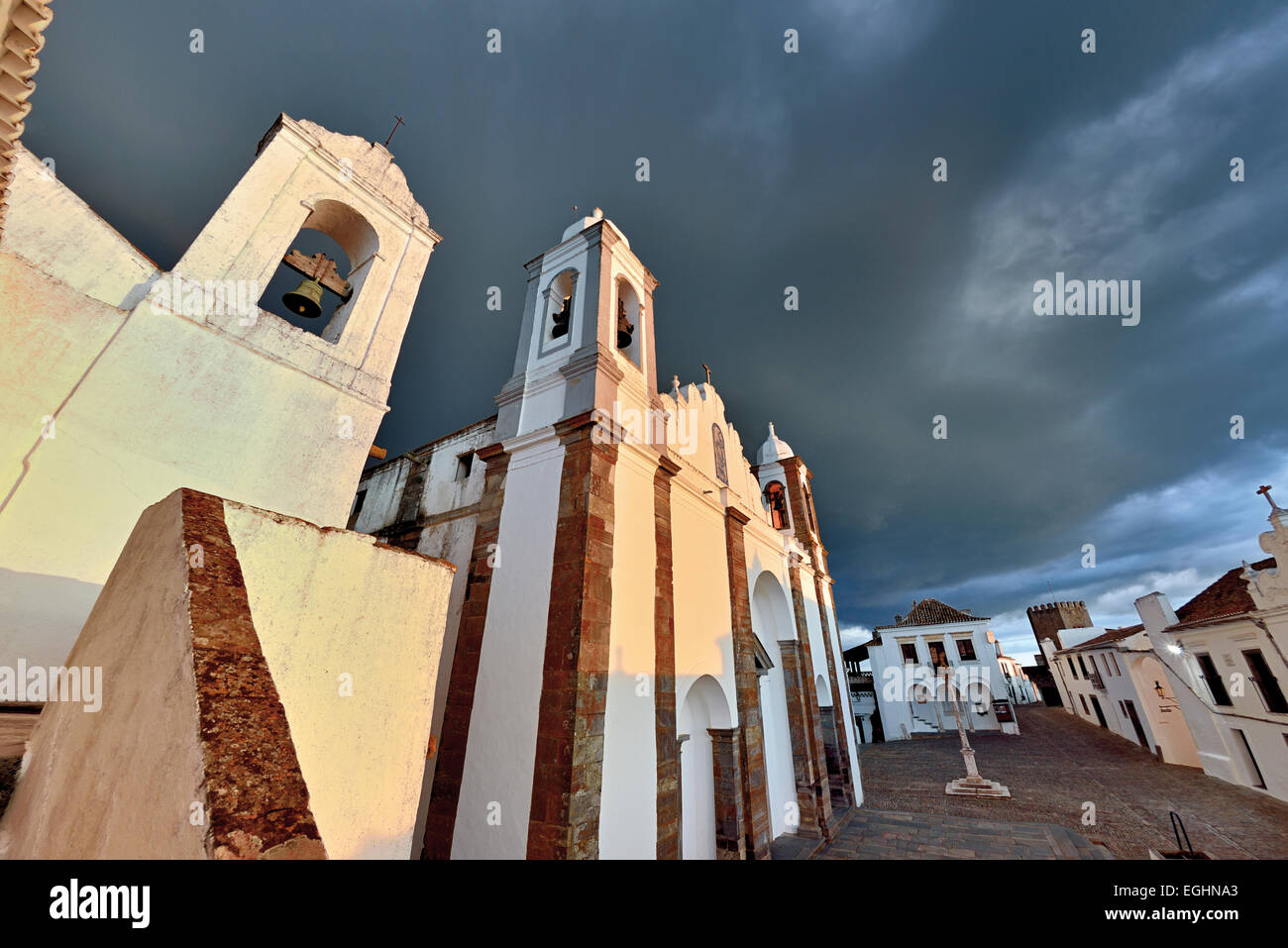 Portogallo Alentejo: Drammatico sky su bianco lavato la chiesa parrocchiale e gli edifici del villaggio storico Monsaraz Foto Stock