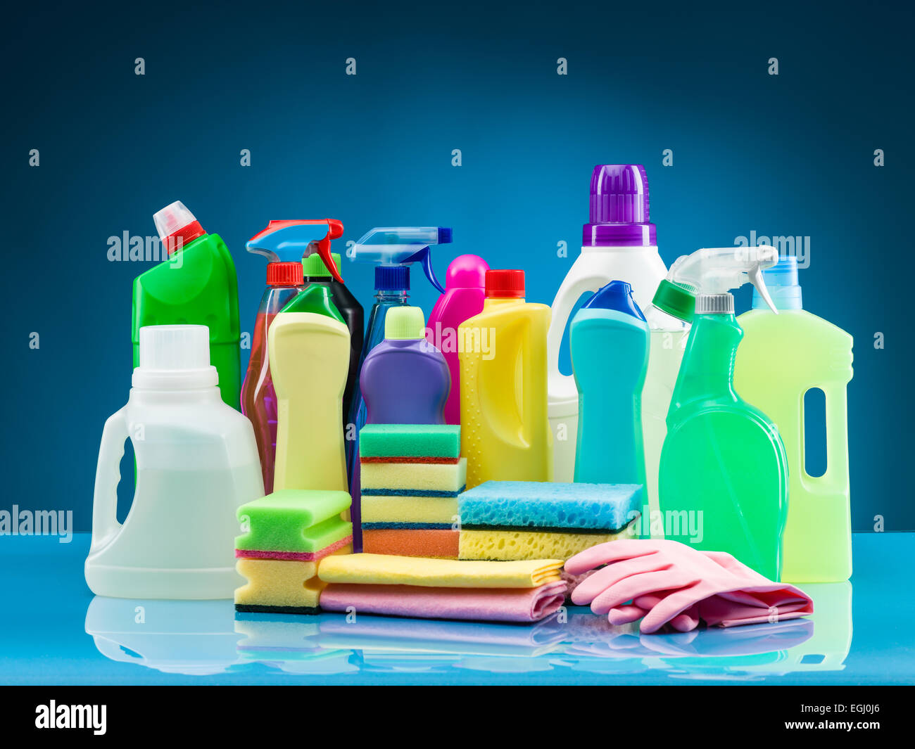 Prodotti di pulizia e i materiali di consumo sulla tavola con sfondo blu Foto Stock