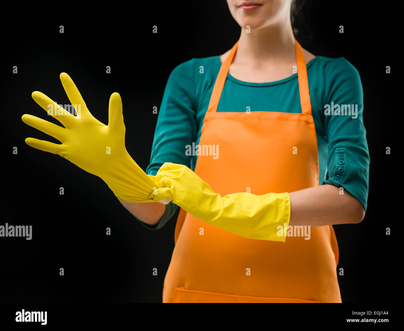 Donna di pulizia di mettere dei guanti di gomma, ottenere pronto per la pulizia, su sfondo nero Foto Stock