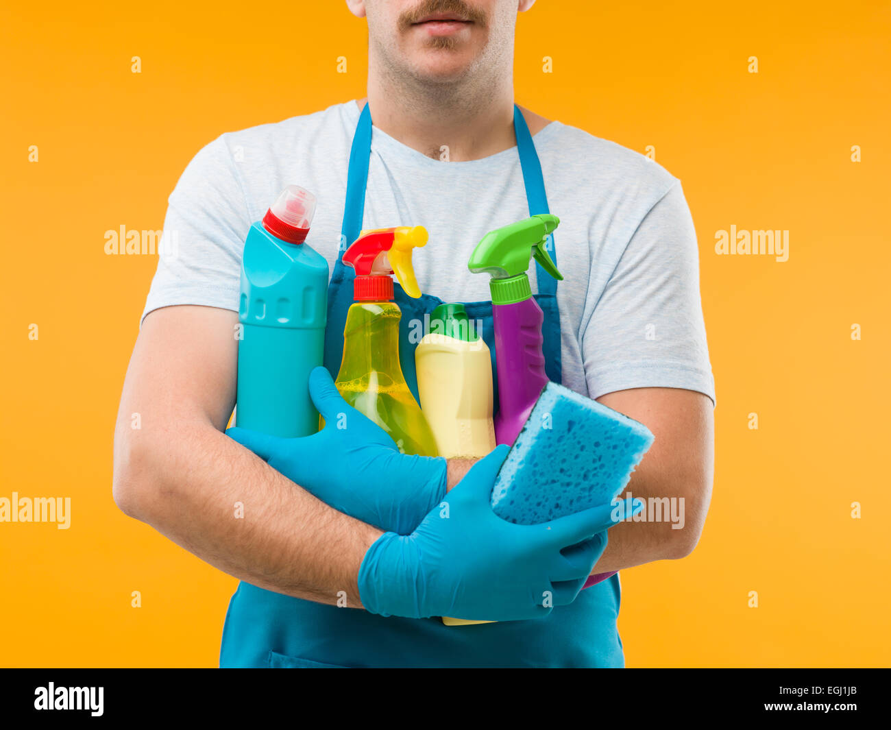 Close-up di maschio caucasico cleaner tenendo molti materiali per la pulizia contro sfondo giallo Foto Stock