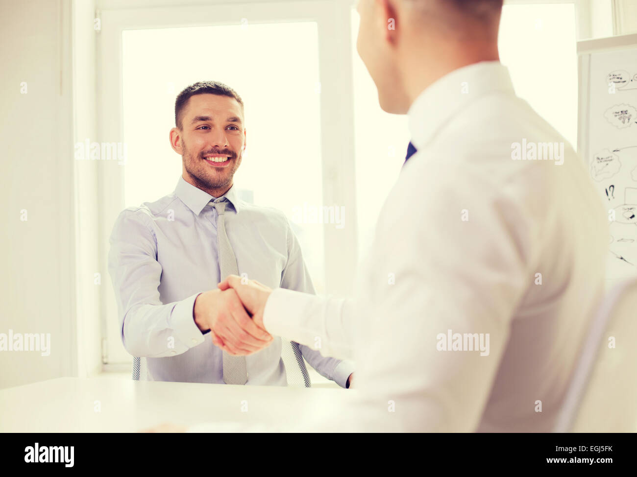 Due imprenditori sorridente stringono le mani in office Foto Stock