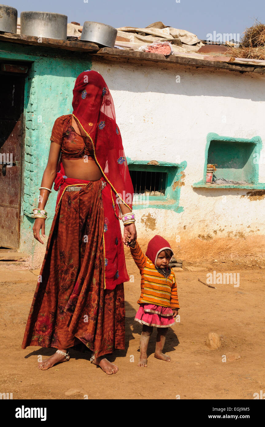 Indian madre e la sua bambina al di fuori del loro tradizionale villaggio tribale home villaggio Kalpi Rajasthan in India Foto Stock