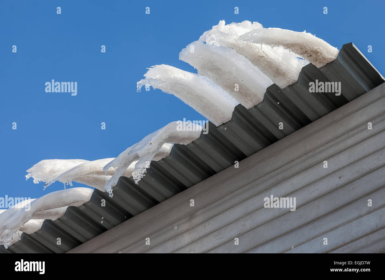 Grandi ghiaccioli appeso sul tetto della casa in primavera Foto Stock