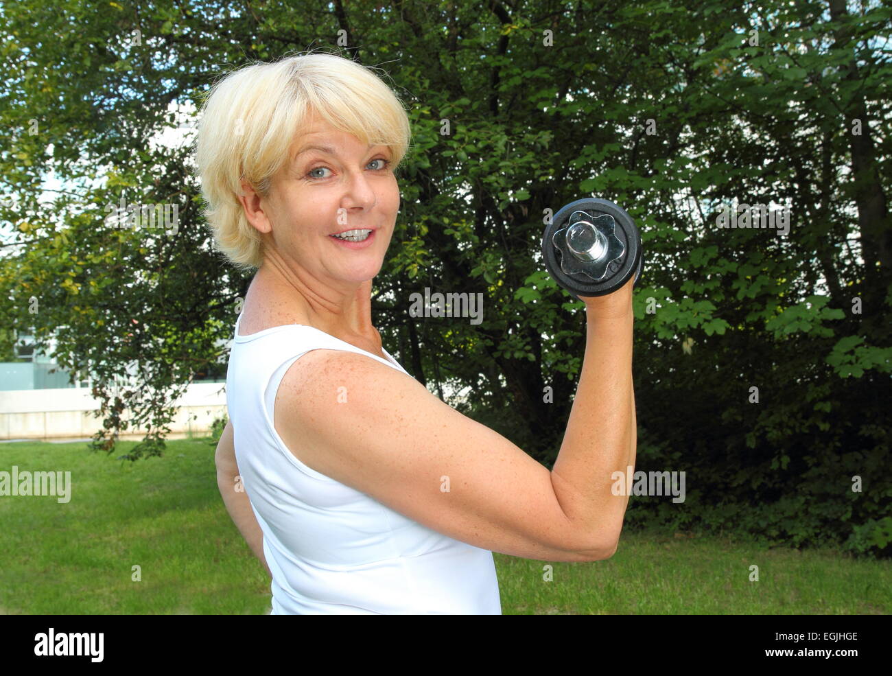 Una donna anziana facendo outdoor training in un parco con il manubrio Foto Stock